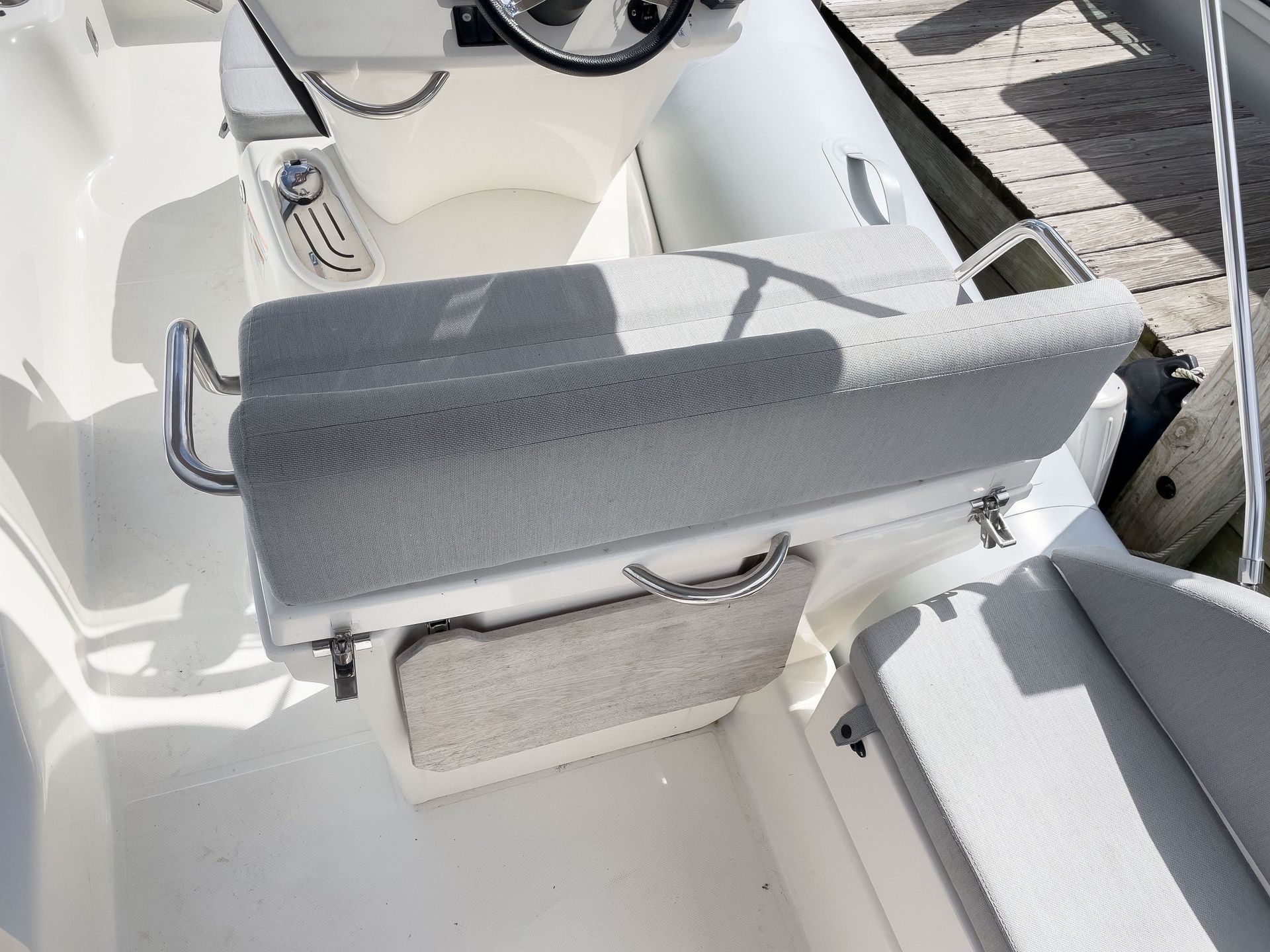 A boat is docked at a dock with a steering wheel and a seat.