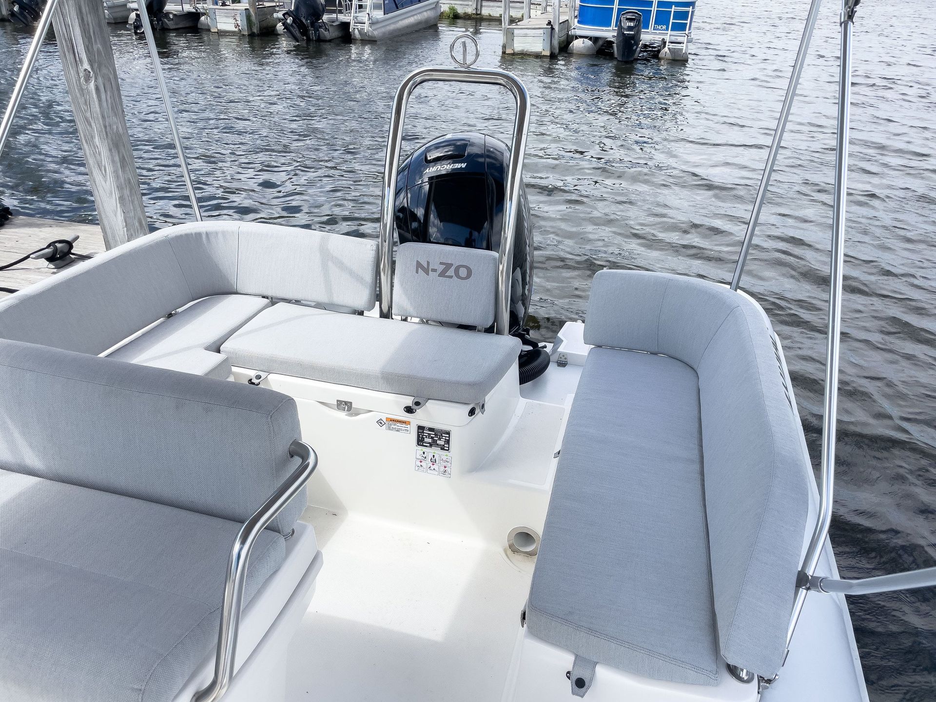 A white boat is docked in the water with a steering wheel.