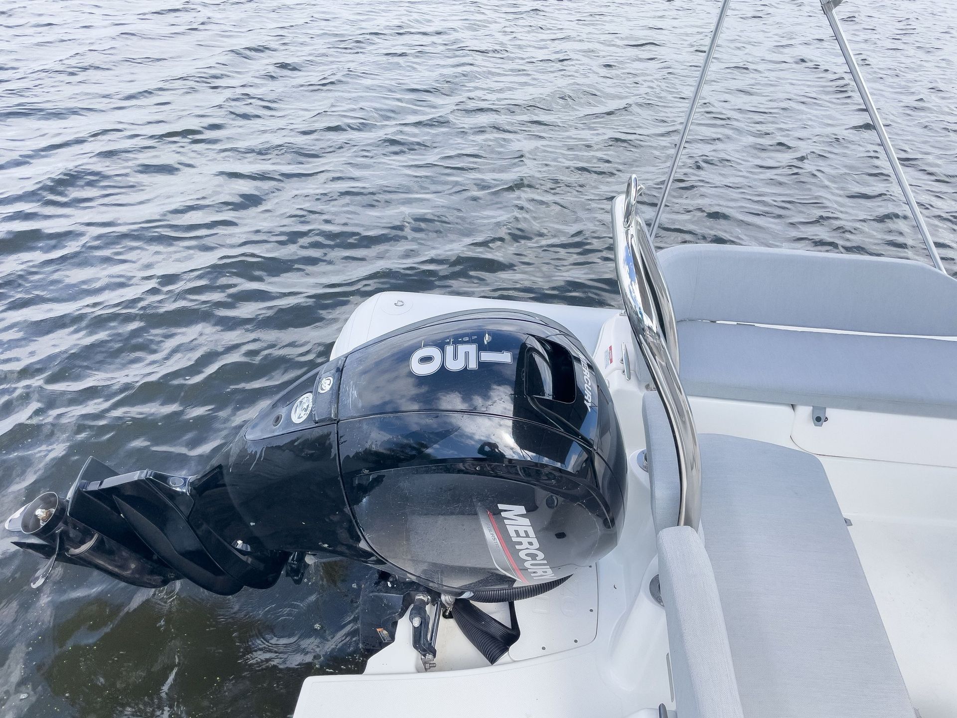 A mercury outboard motor is sitting on the side of a boat in the water.