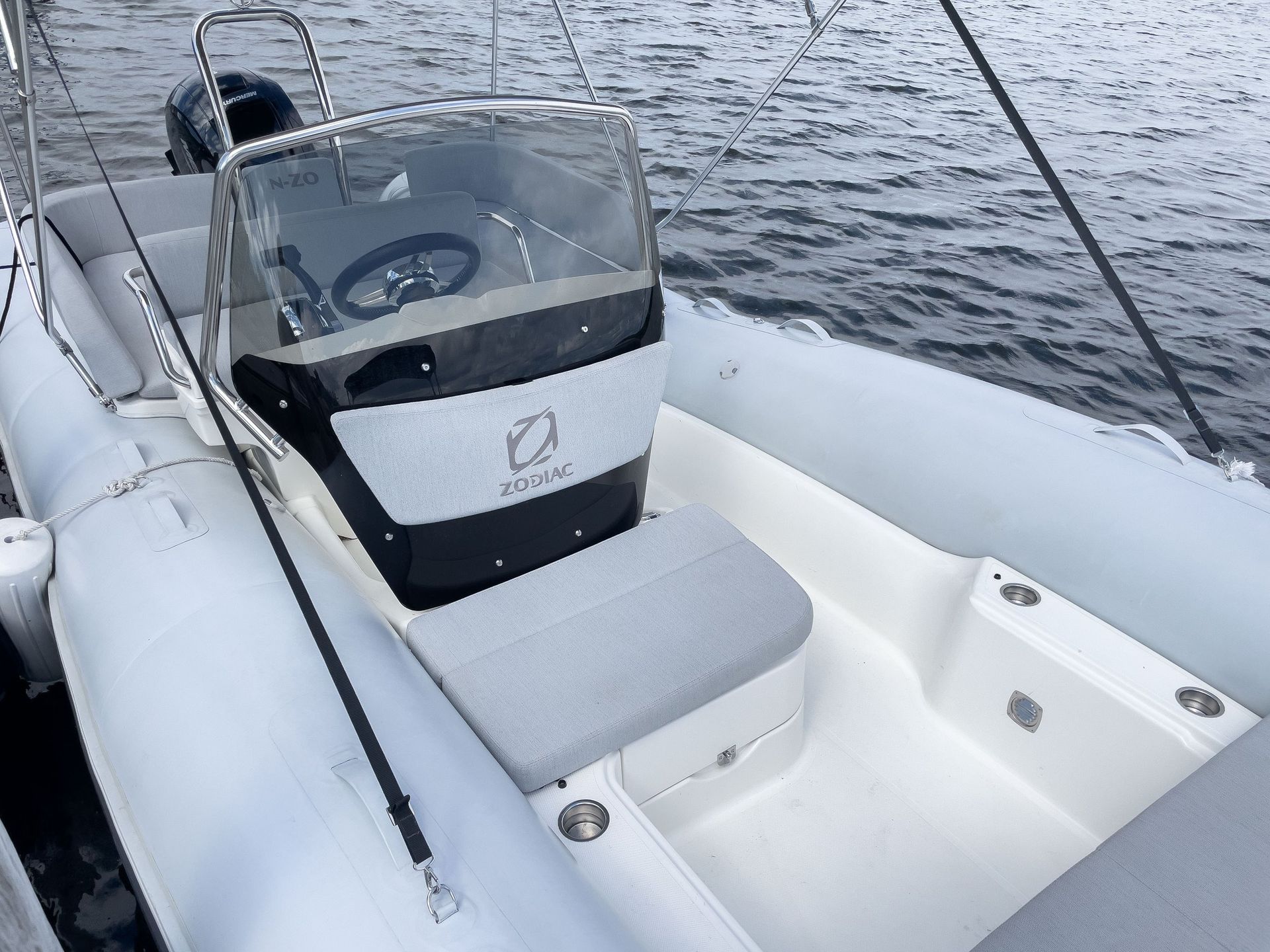 A white boat with a steering wheel is in the water