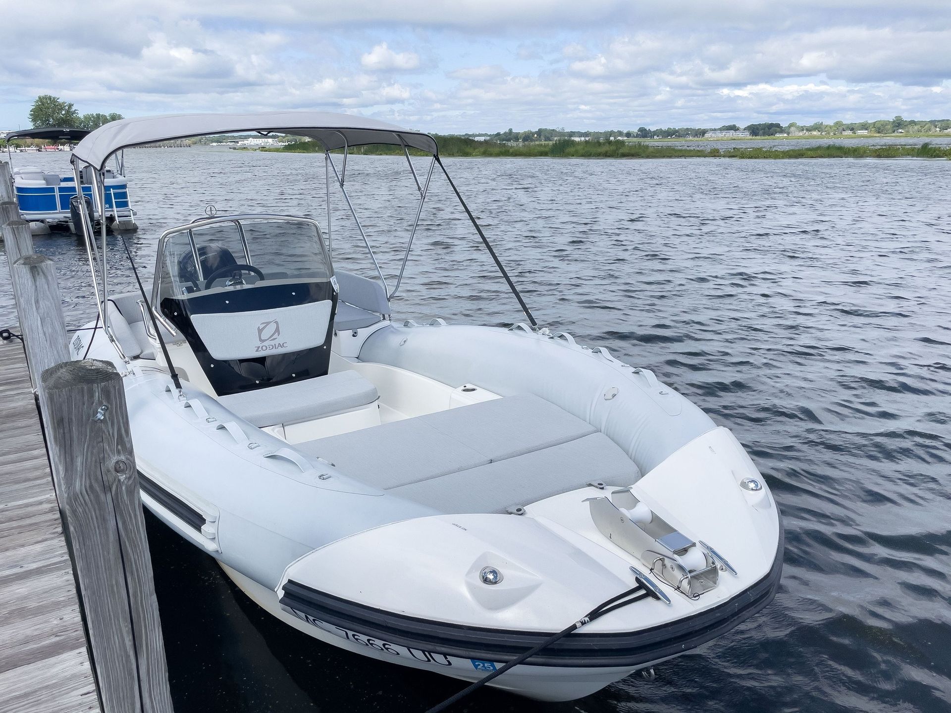 A white boat is docked at a dock on a lake.