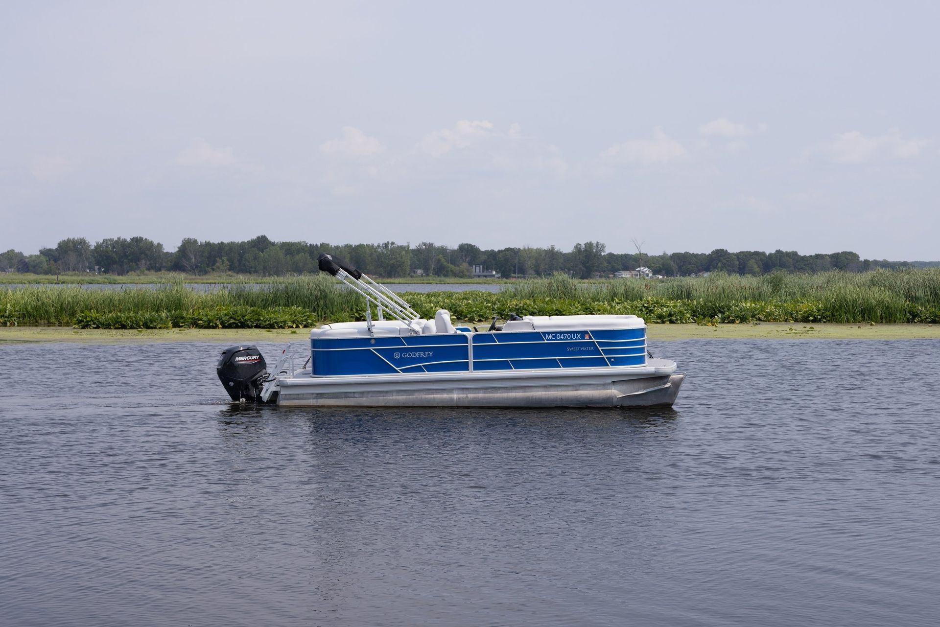 A blue and white pontoon boat is floating on a lake