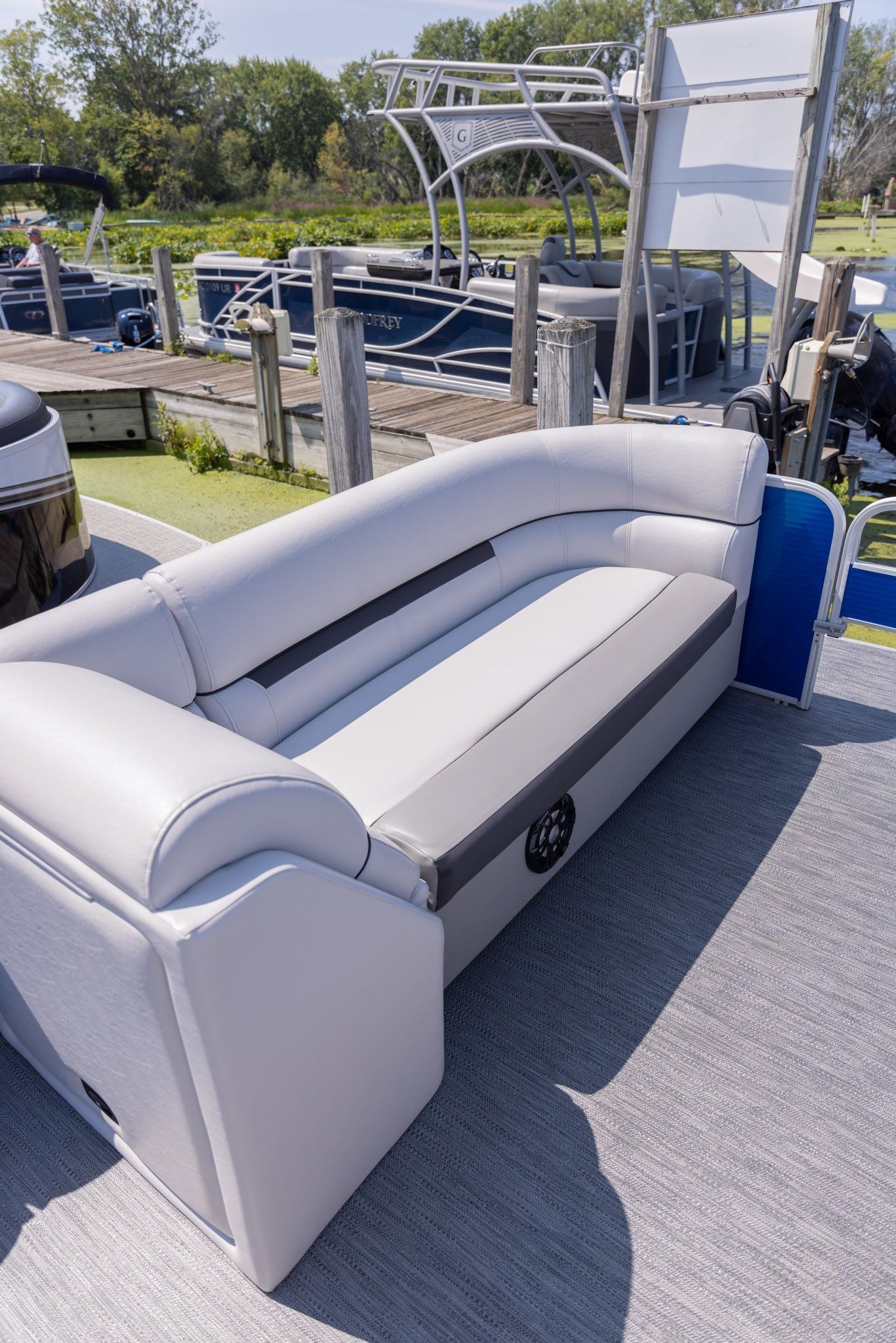 A couch is sitting on the deck of a pontoon boat.