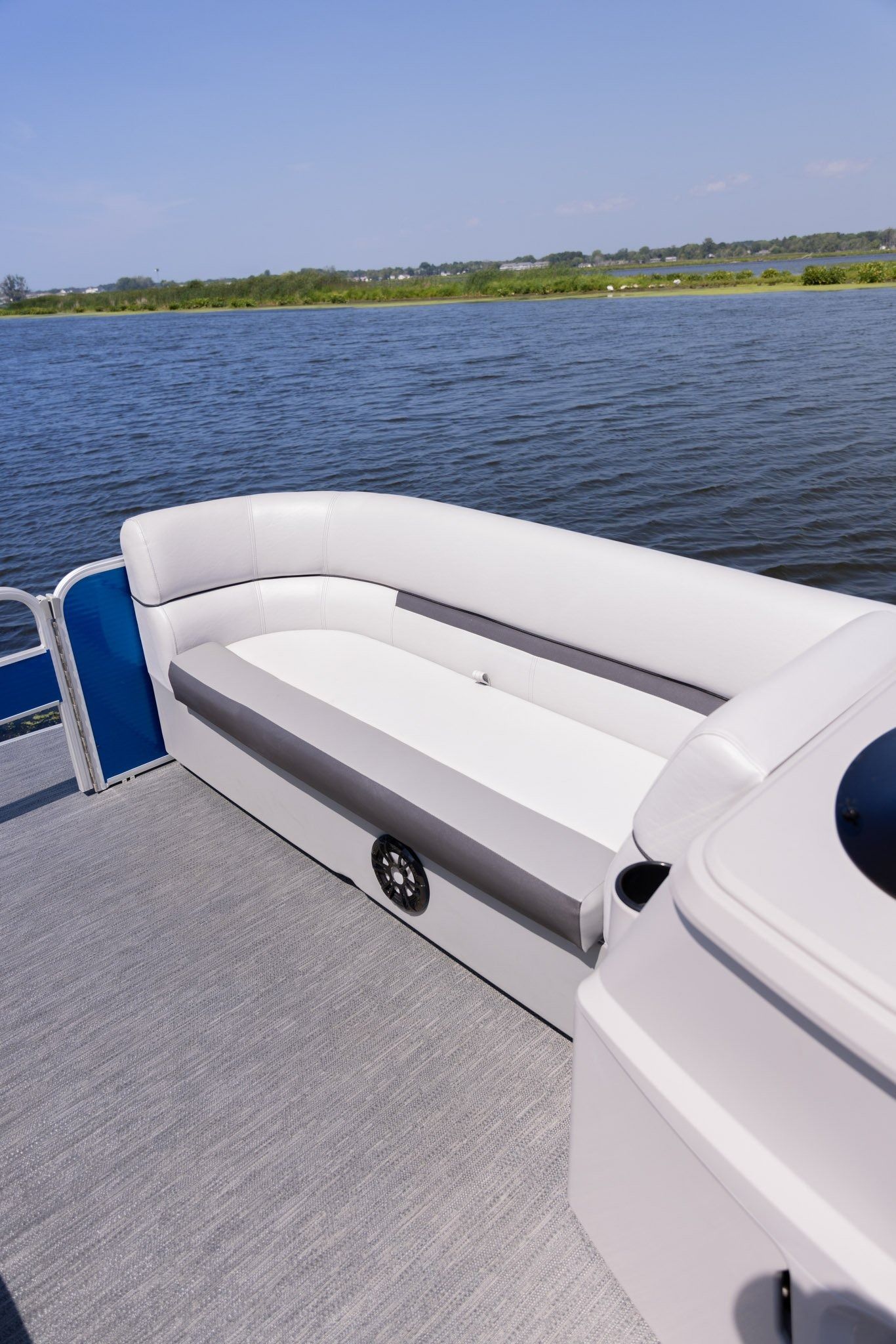 A white pontoon boat is floating on top of a lake.