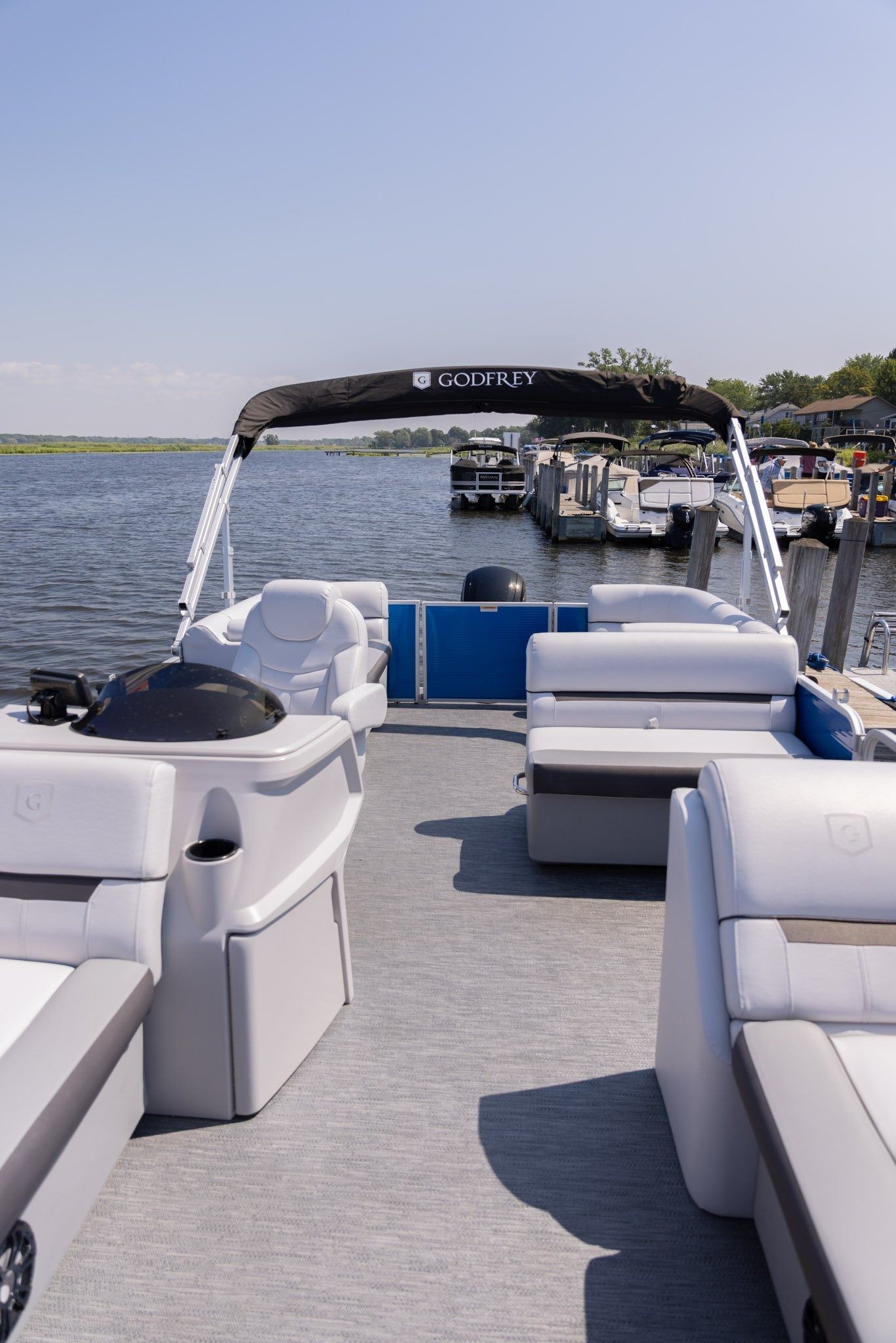 A pontoon boat is docked at a marina on a lake.