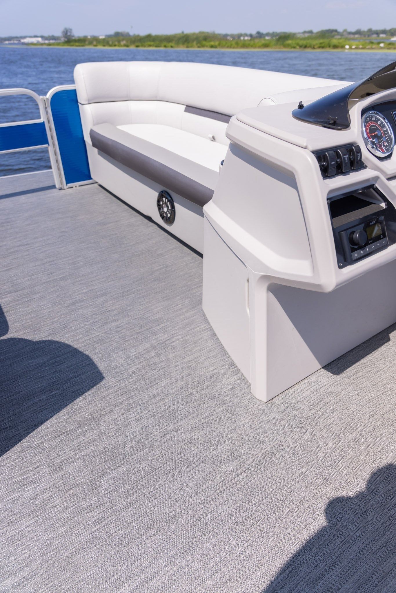 A pontoon boat with a couch and a steering wheel on the deck.