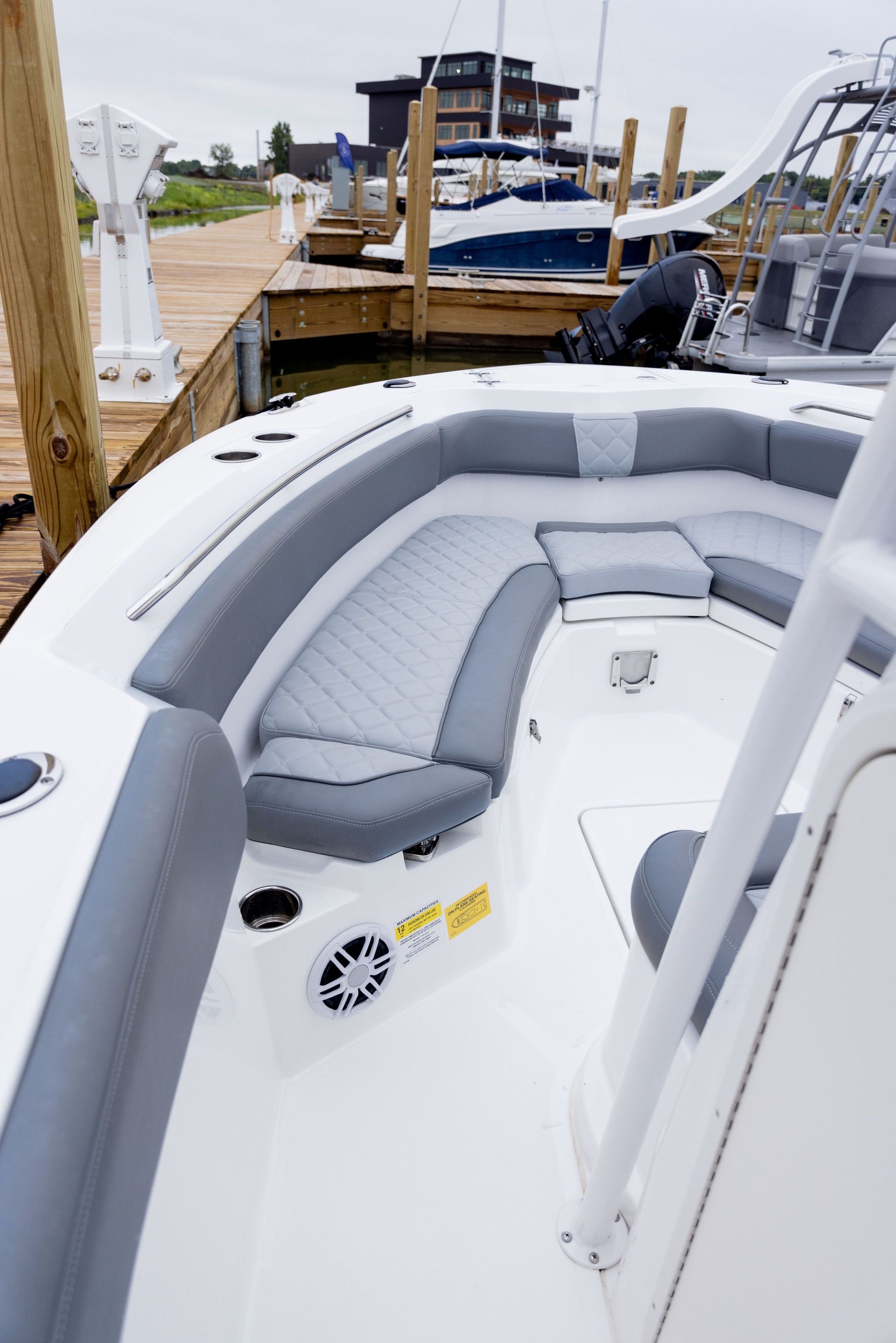 A white boat with gray seats is docked at a marina.