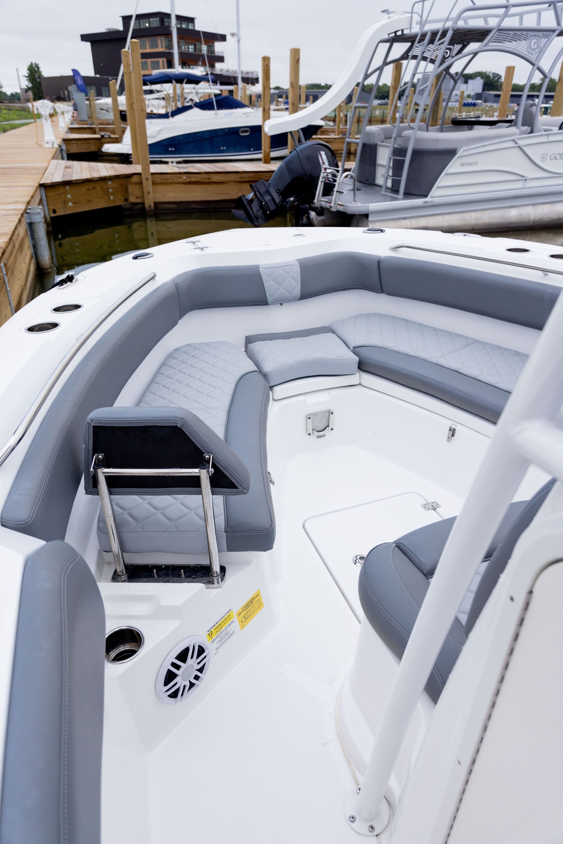 A white boat with gray seats is docked at a marina.