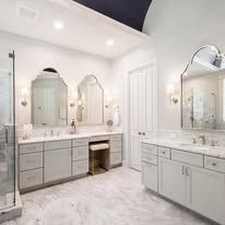 Bright white double vanity bathroom with marble counters, mirrors, and recessed lighting