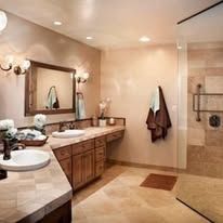 Spacious beige bathroom with double vanity, large mirror, walk-in shower, and towels on wall.