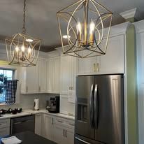 Modern kitchen with white cabinets, stainless steel fridge, and gold geometric pendant lights