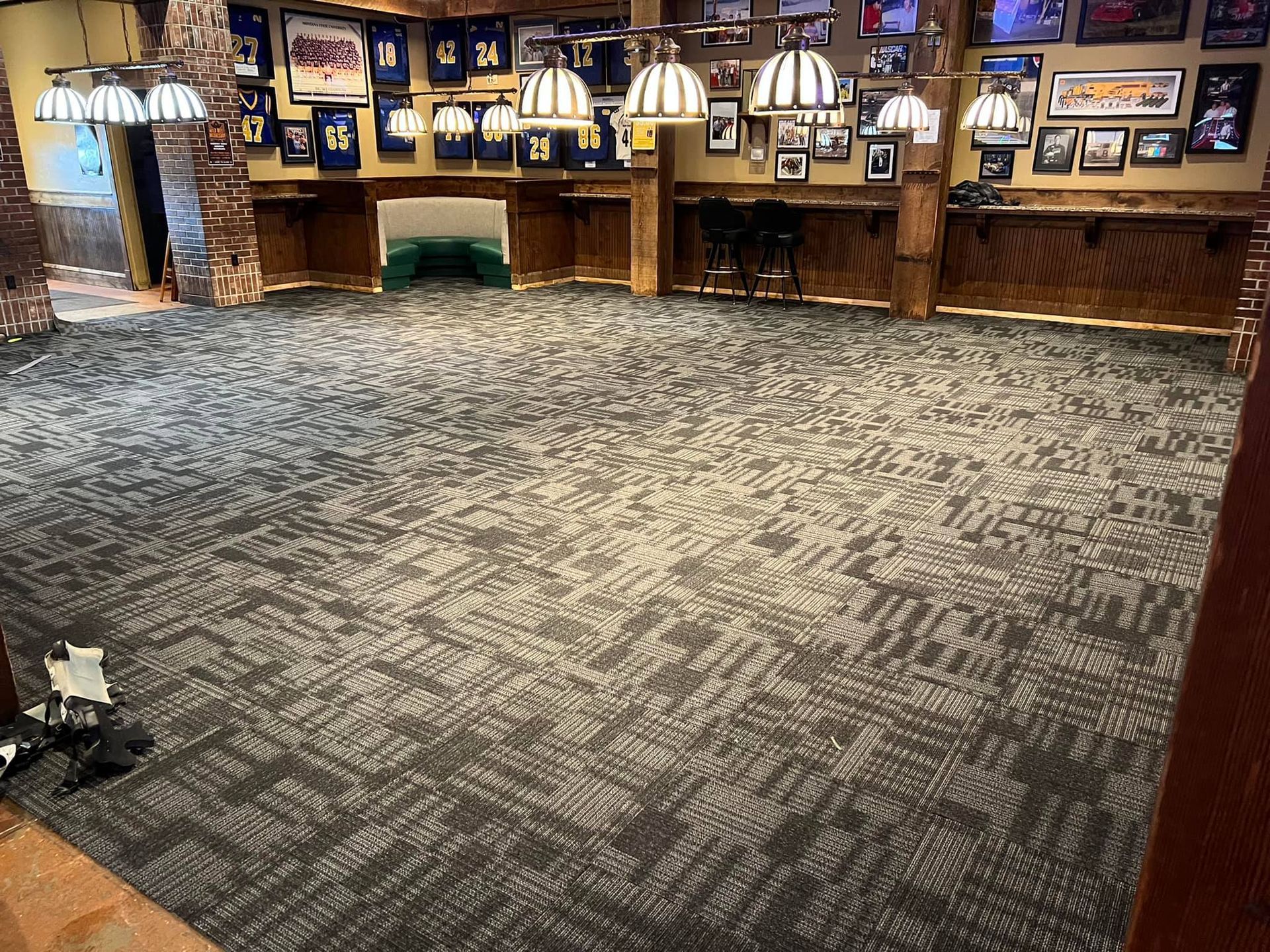 Empty carpeted restaurant with framed photos and hanging lights along the back wall