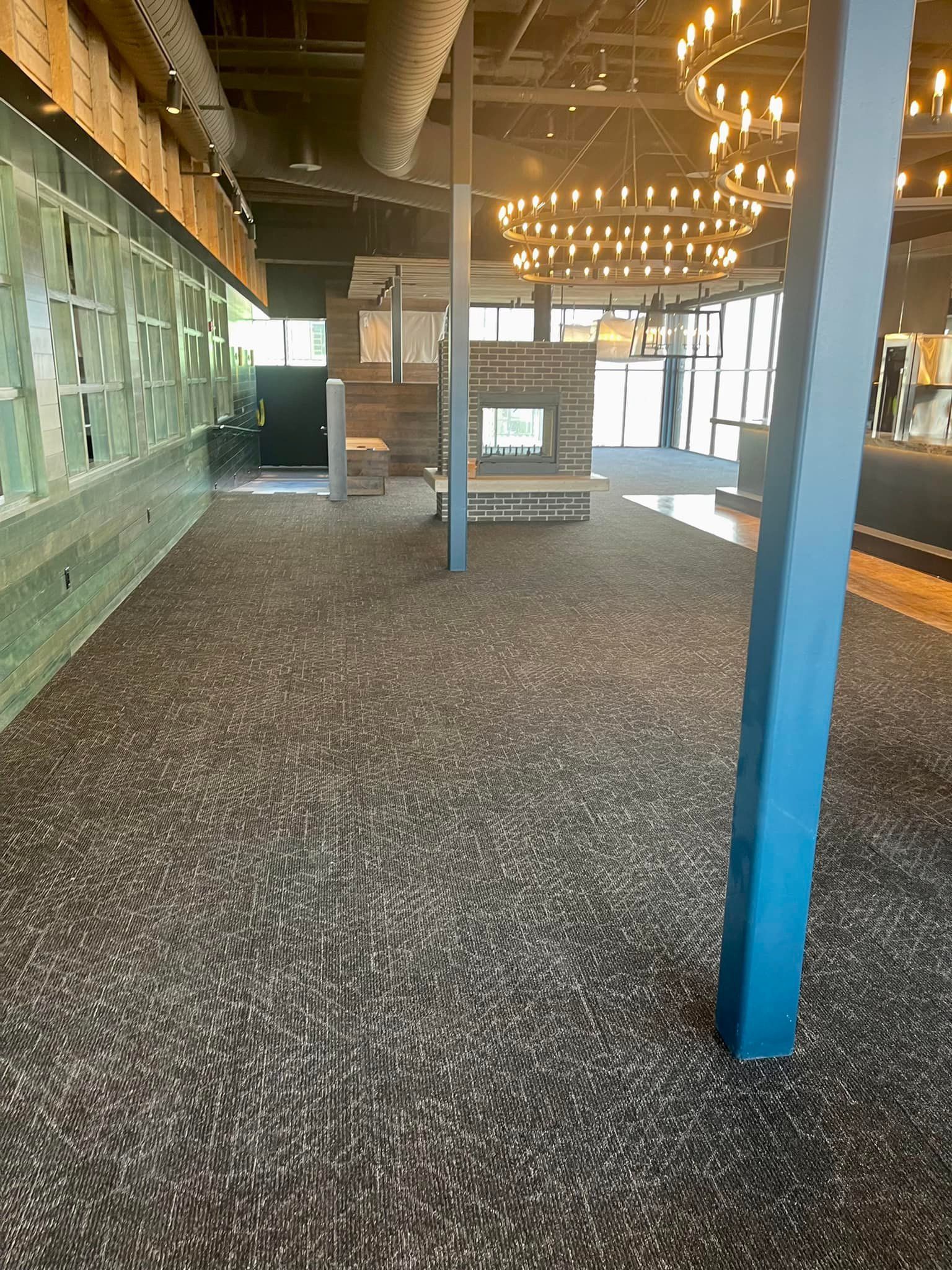 Empty interior with patterned carpet, exposed ceiling, and blue support columns, lit by circular hanging lights