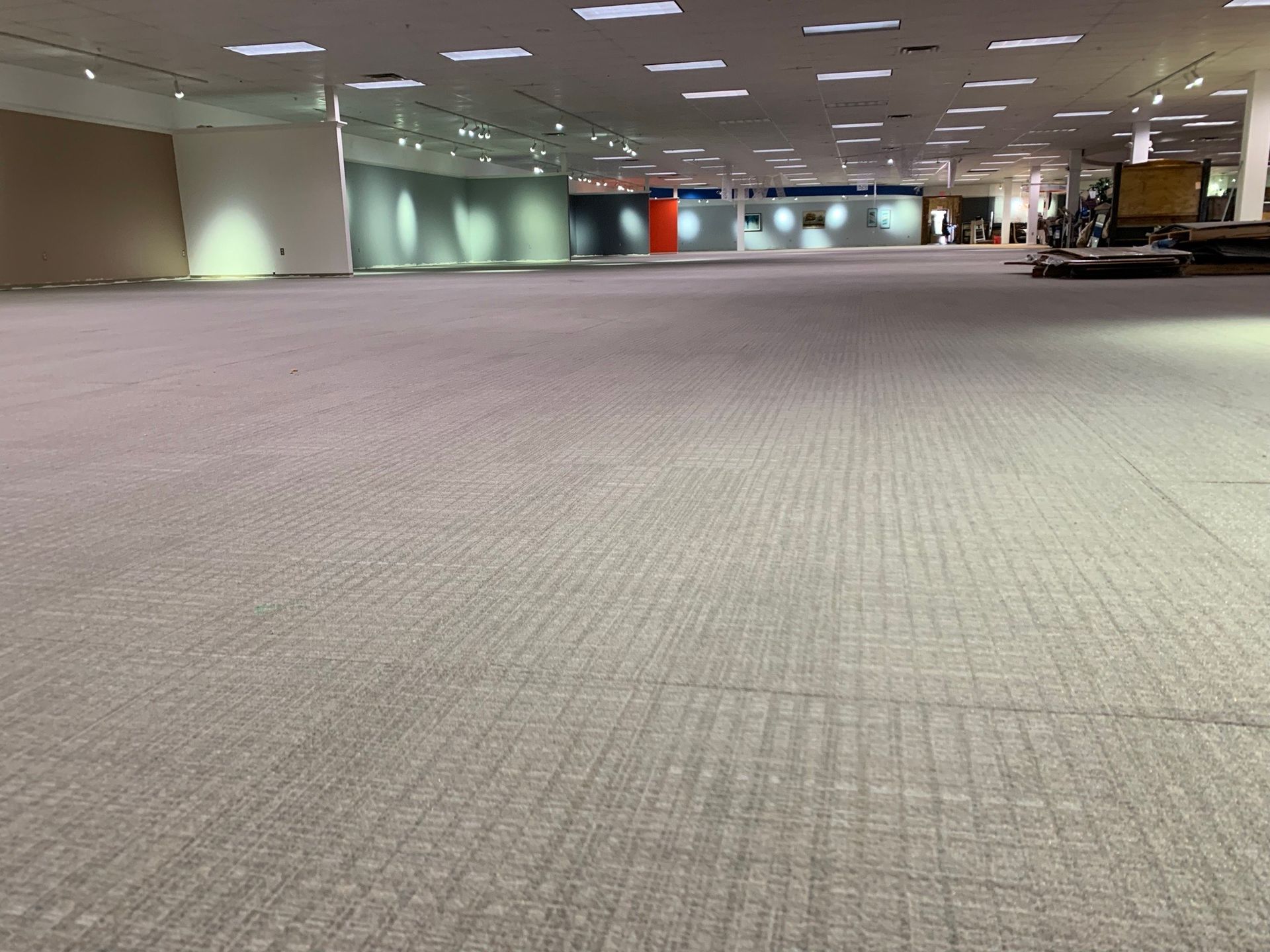 Empty indoor hall with carpeted floor, low ceiling lights, and distant colorful wall sections