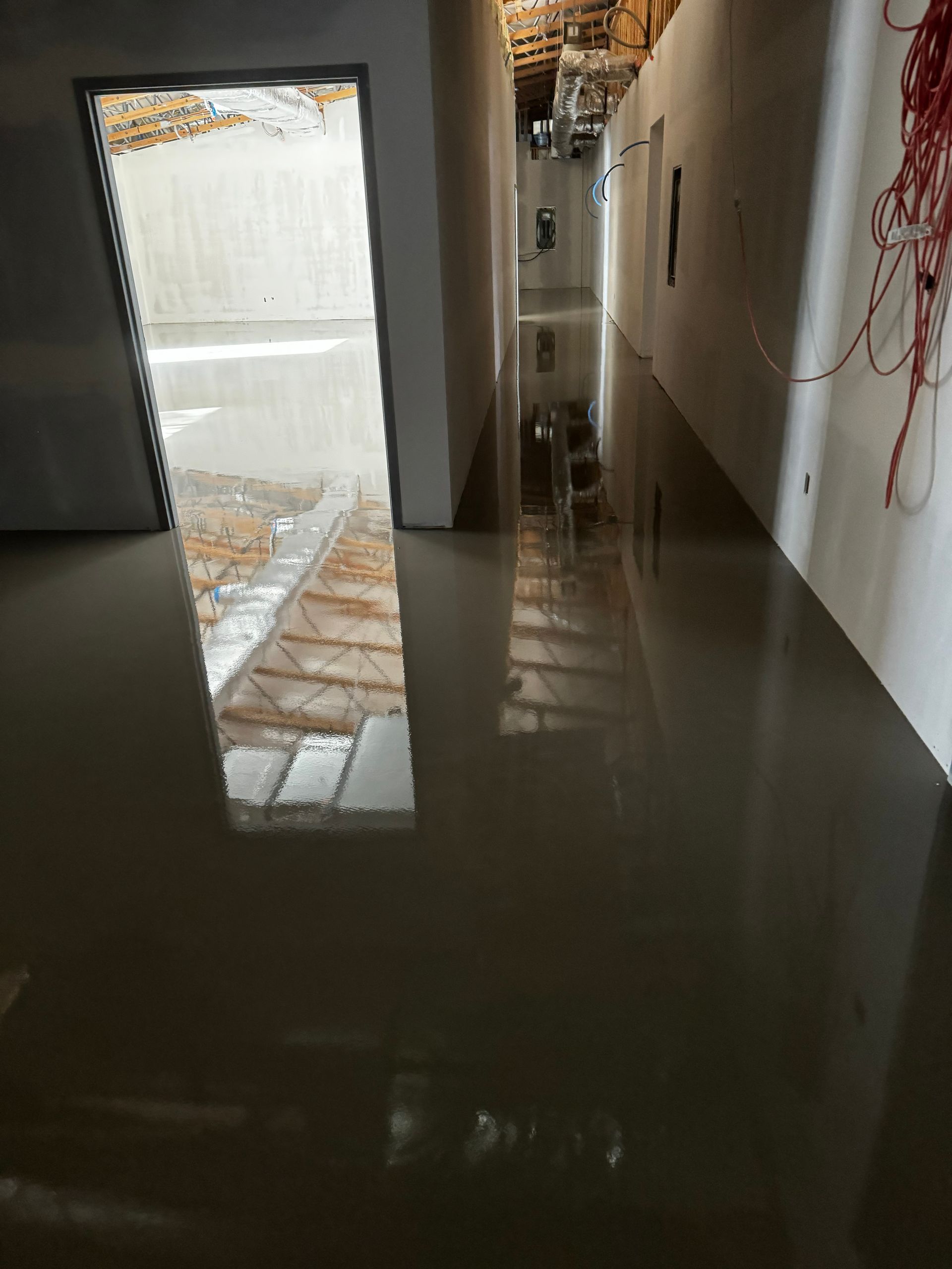 Empty room with a newly finished glossy gray floor and a bright doorway.
