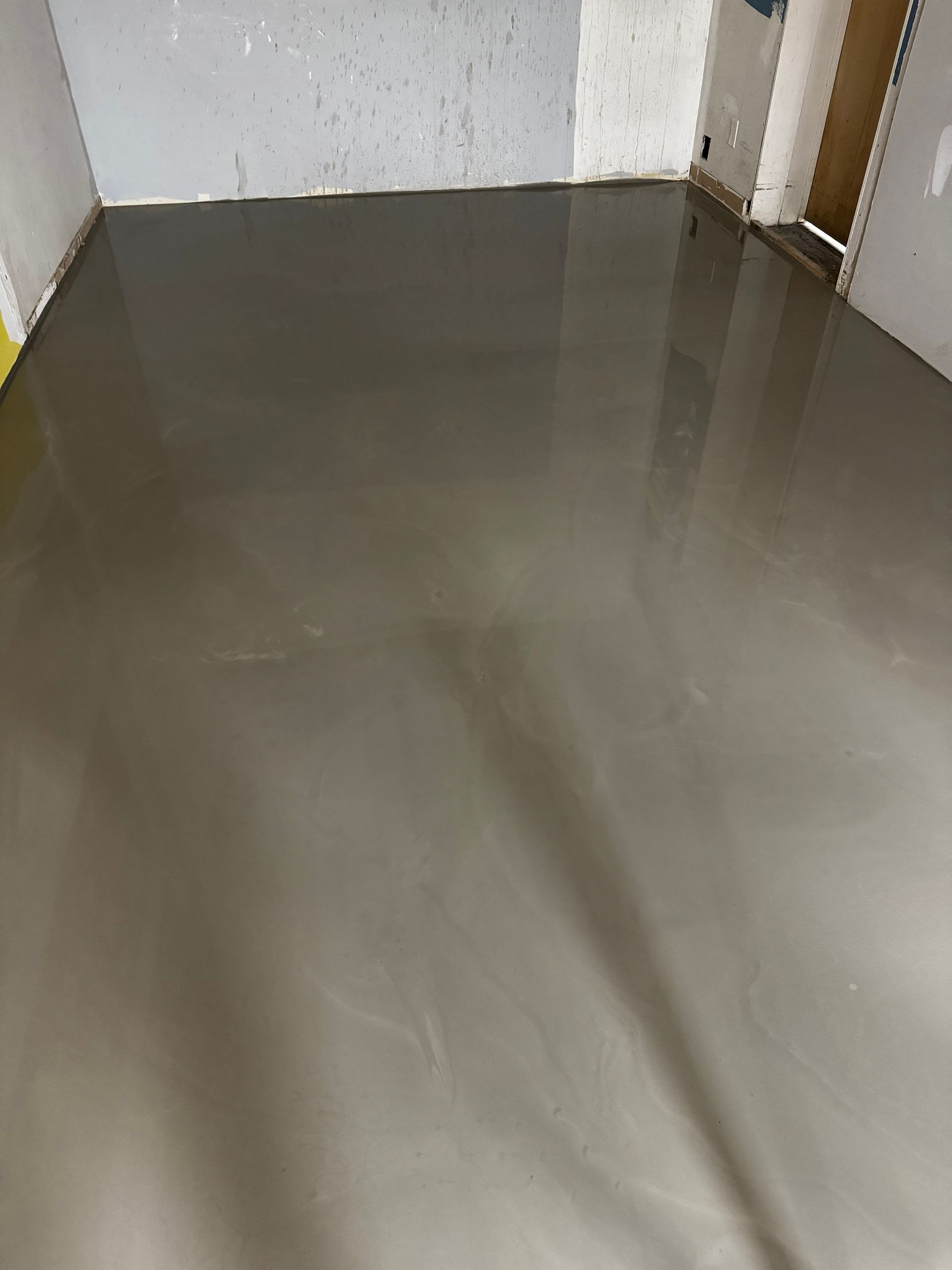 Empty room with a newly finished glossy gray concrete floor and white walls.
