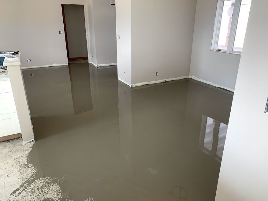 Flooded interior room with standing gray water reflecting windows and walls