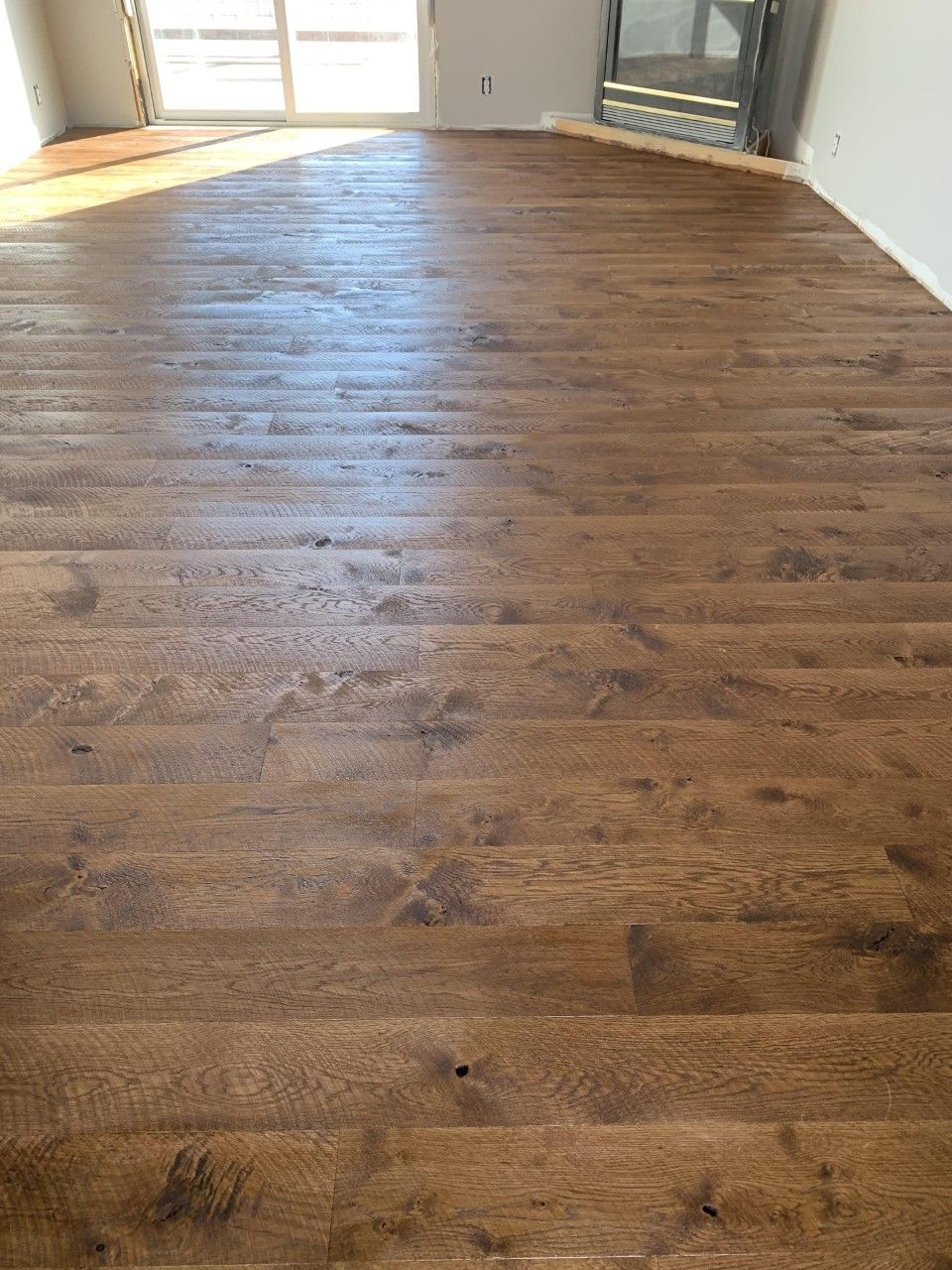 Empty room with dark wood floors and bright sunlight from the windows