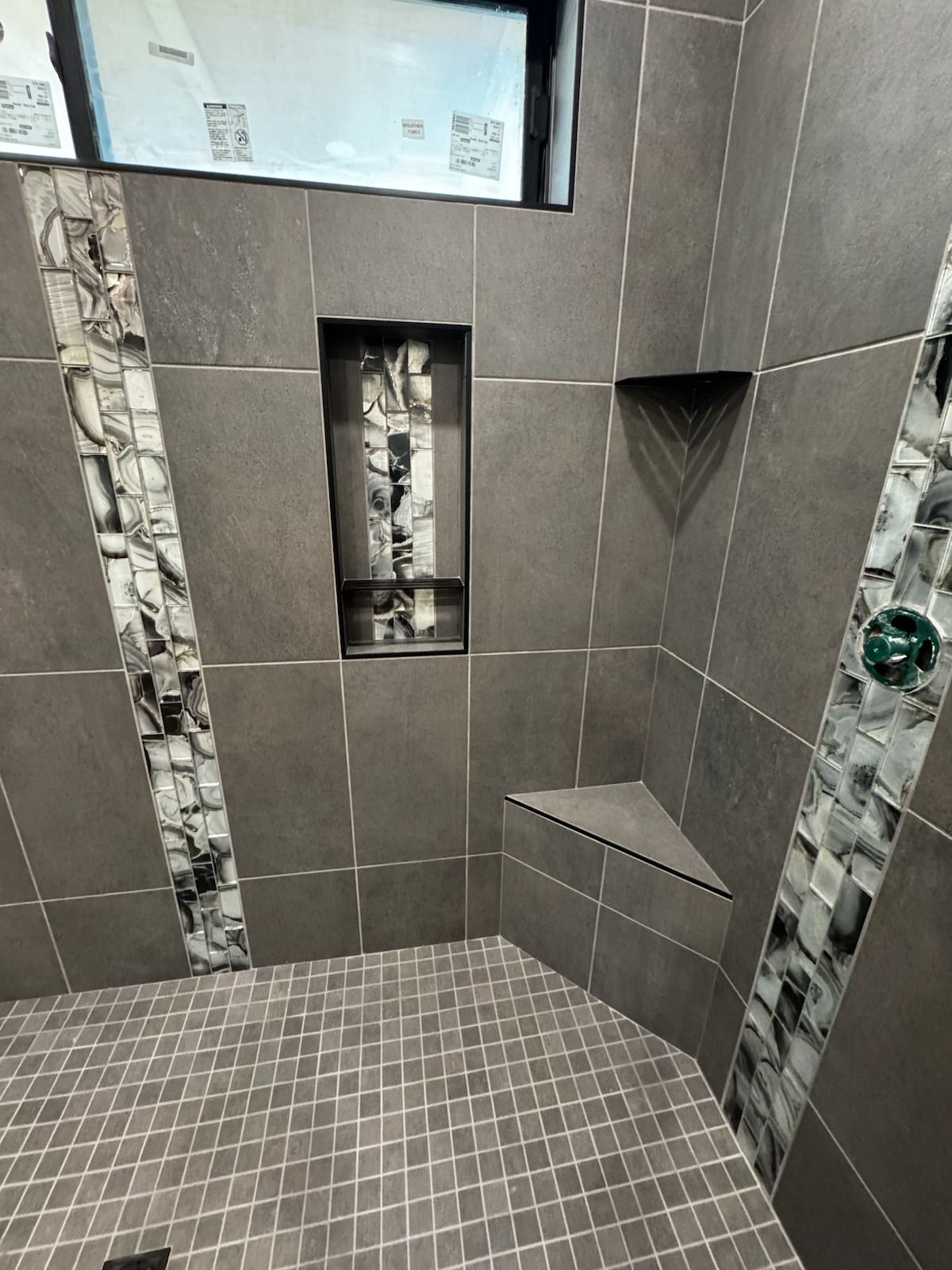 Tiled shower stall with recessed shelf and soap niche in gray and mosaic tiles