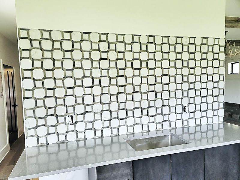 Modern kitchen with geometric tiled backsplash, stainless sink, and gray countertop