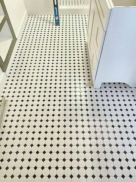 Black-and-white tiled floor in a bathroom or hallway, with a mop visible near the back.