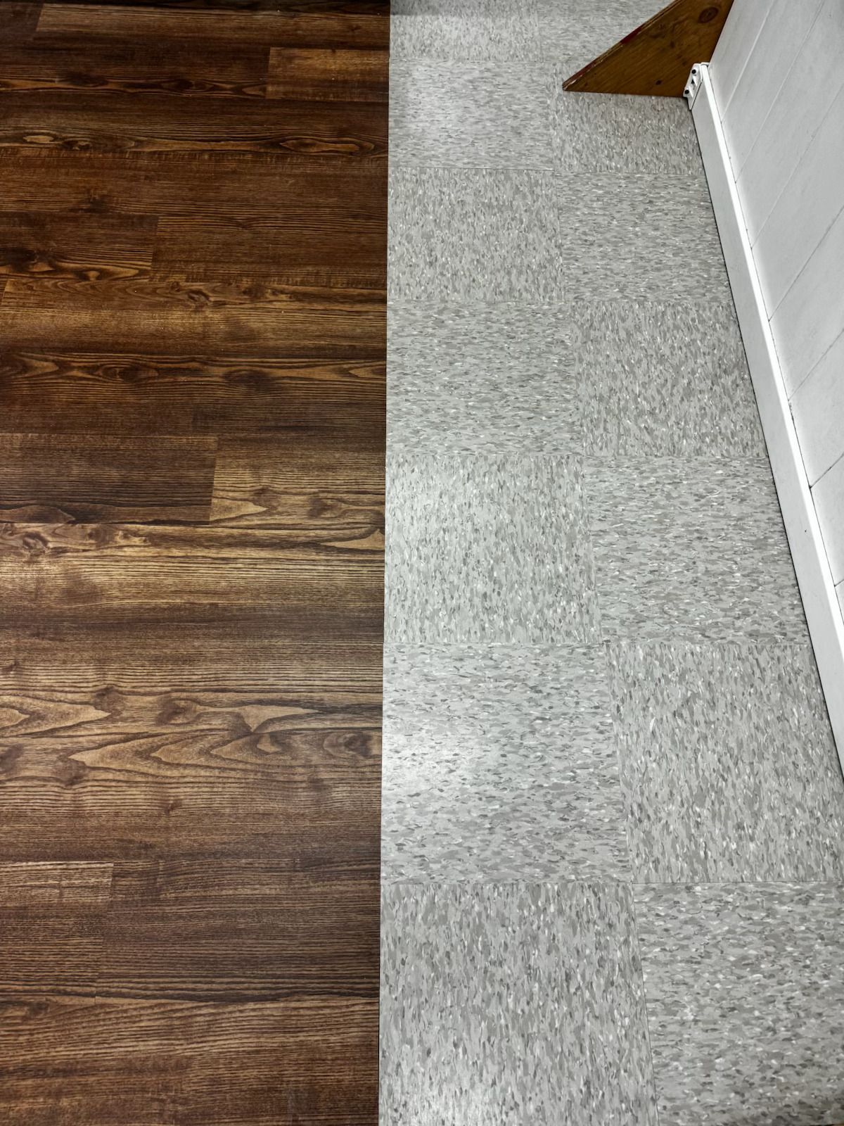 Wooden floor meeting light gray carpet at a doorway with a white wall trim.