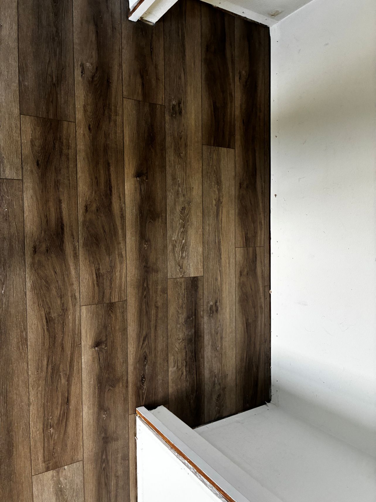 Dark wood-paneled wall beside a white staircase in a modern interior