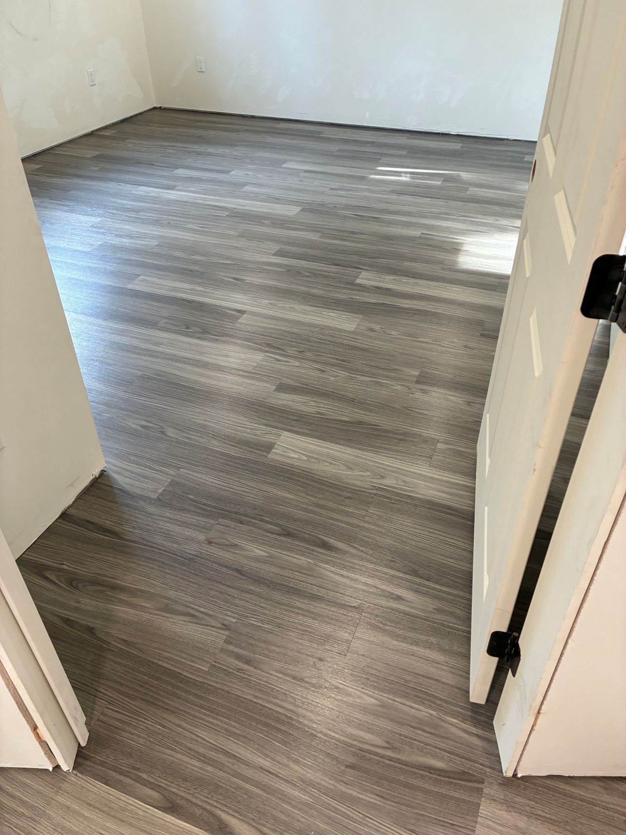 Empty room with gray wood flooring and an open doorway in the foreground