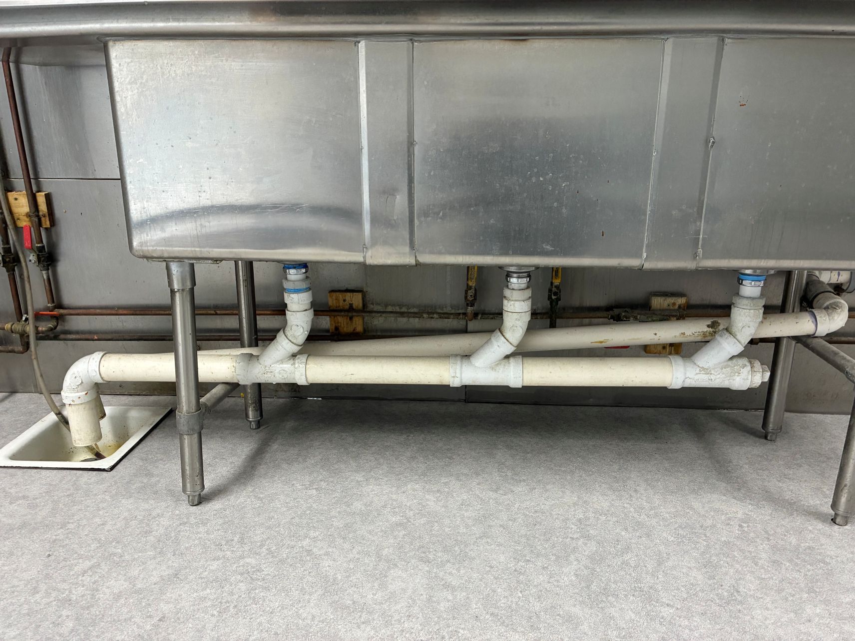 Industrial metal tank with white pipes and a lower support frame in a utility room