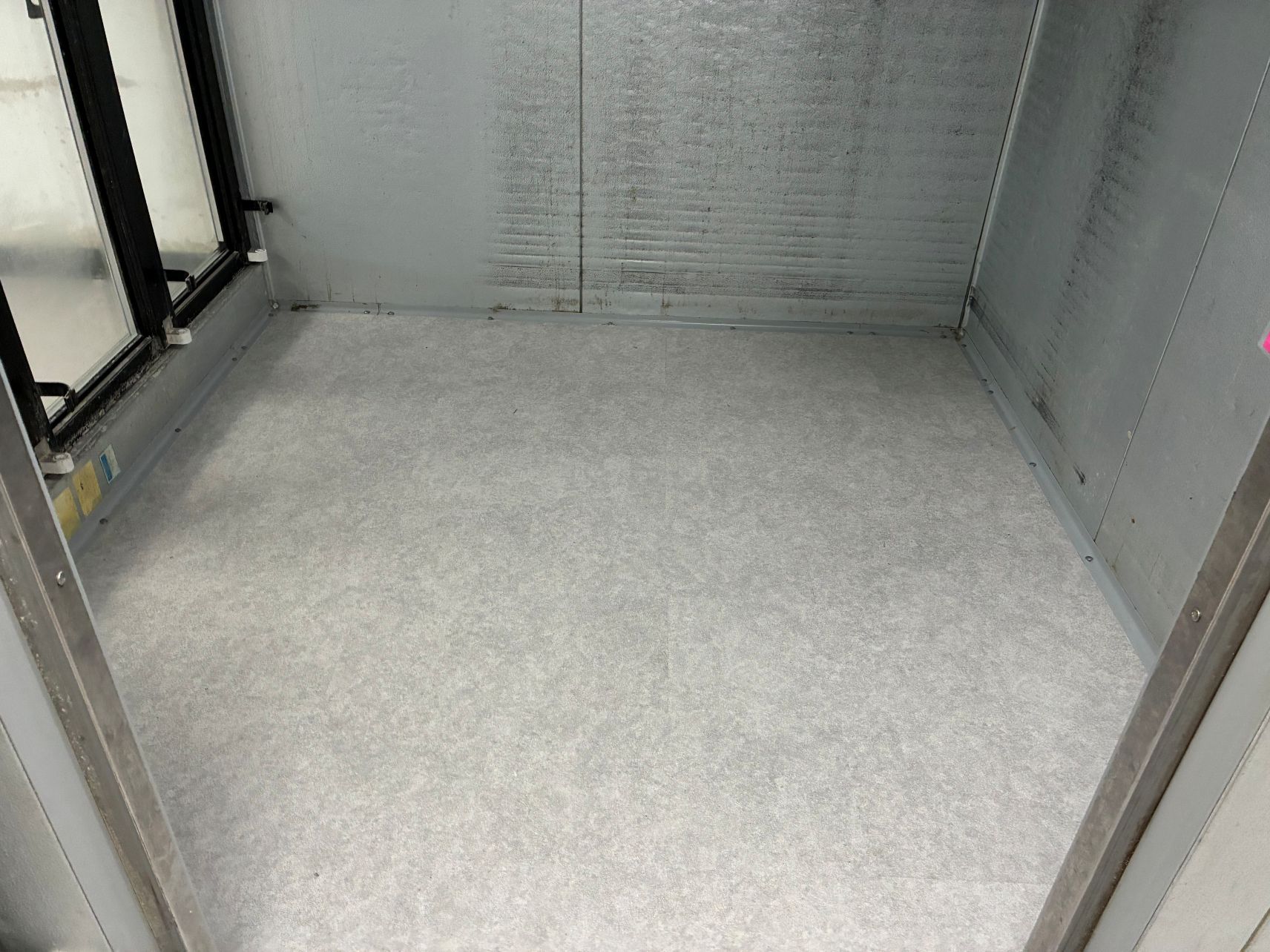 Empty gray cargo or elevator floor with metal walls and door frame