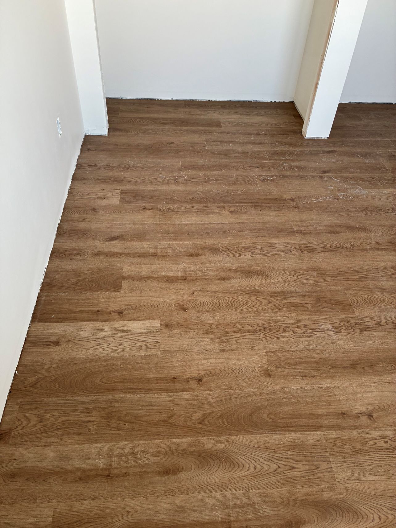Empty hallway with brown wood-look flooring and white walls