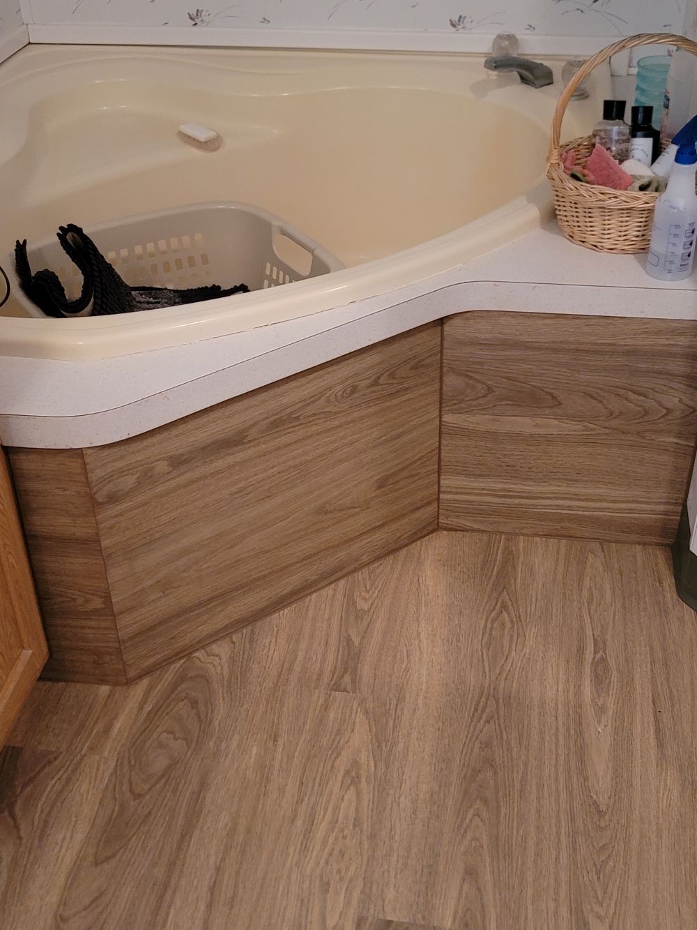 Corner bathtub with wood-paneled side and tan floor tiles in a bathroom
