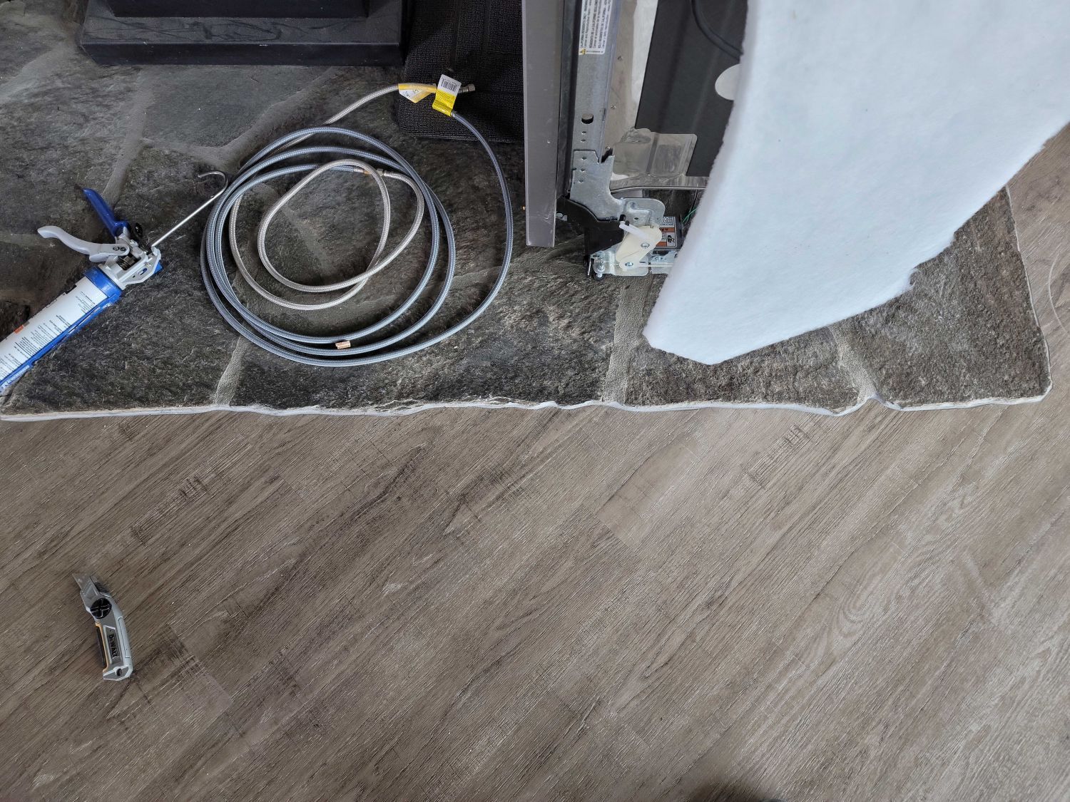Coiled hoses and tools on a floor where carpet meets wood flooring during renovation work