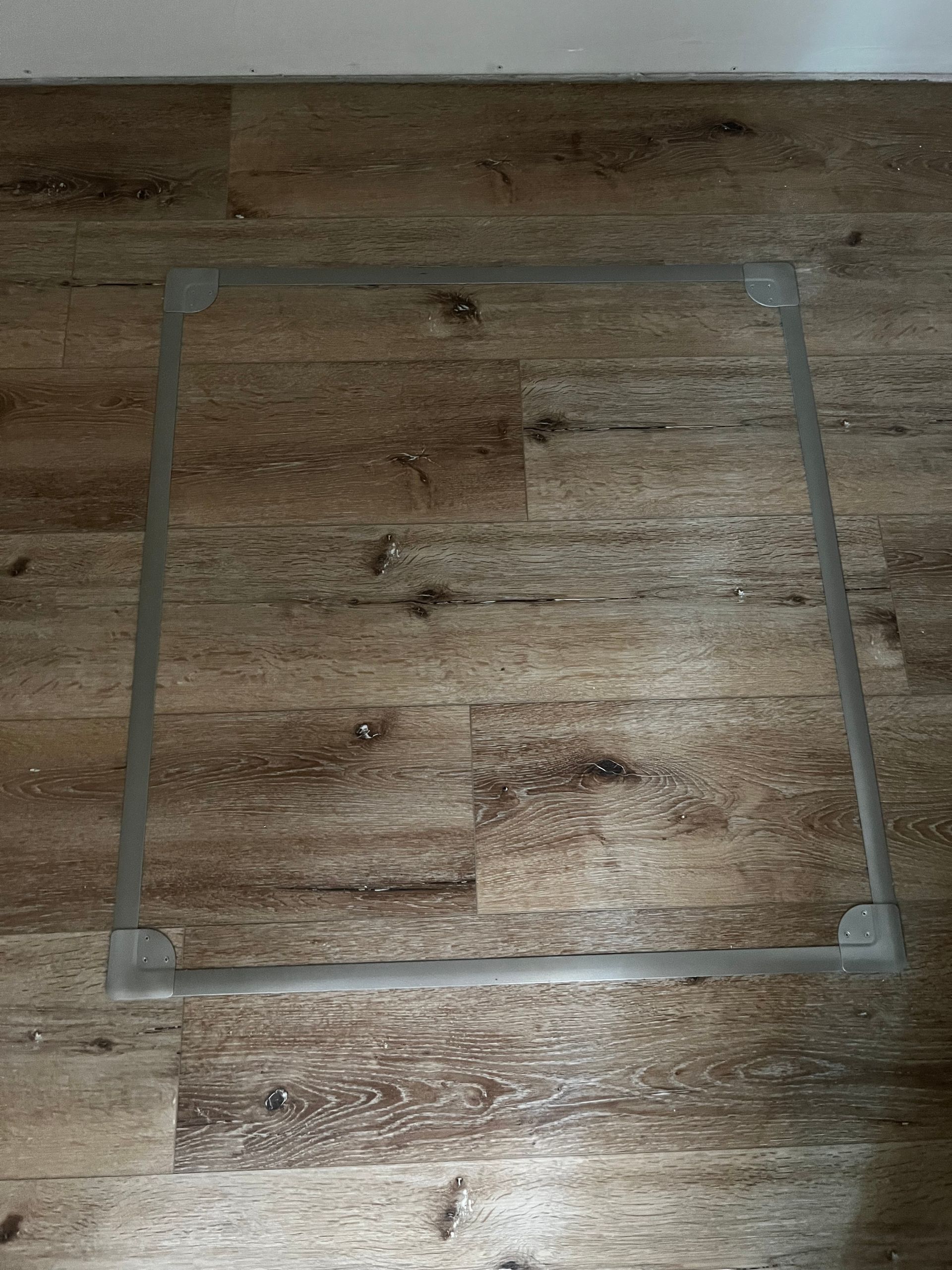 Square outline of clear tape on a wooden floor