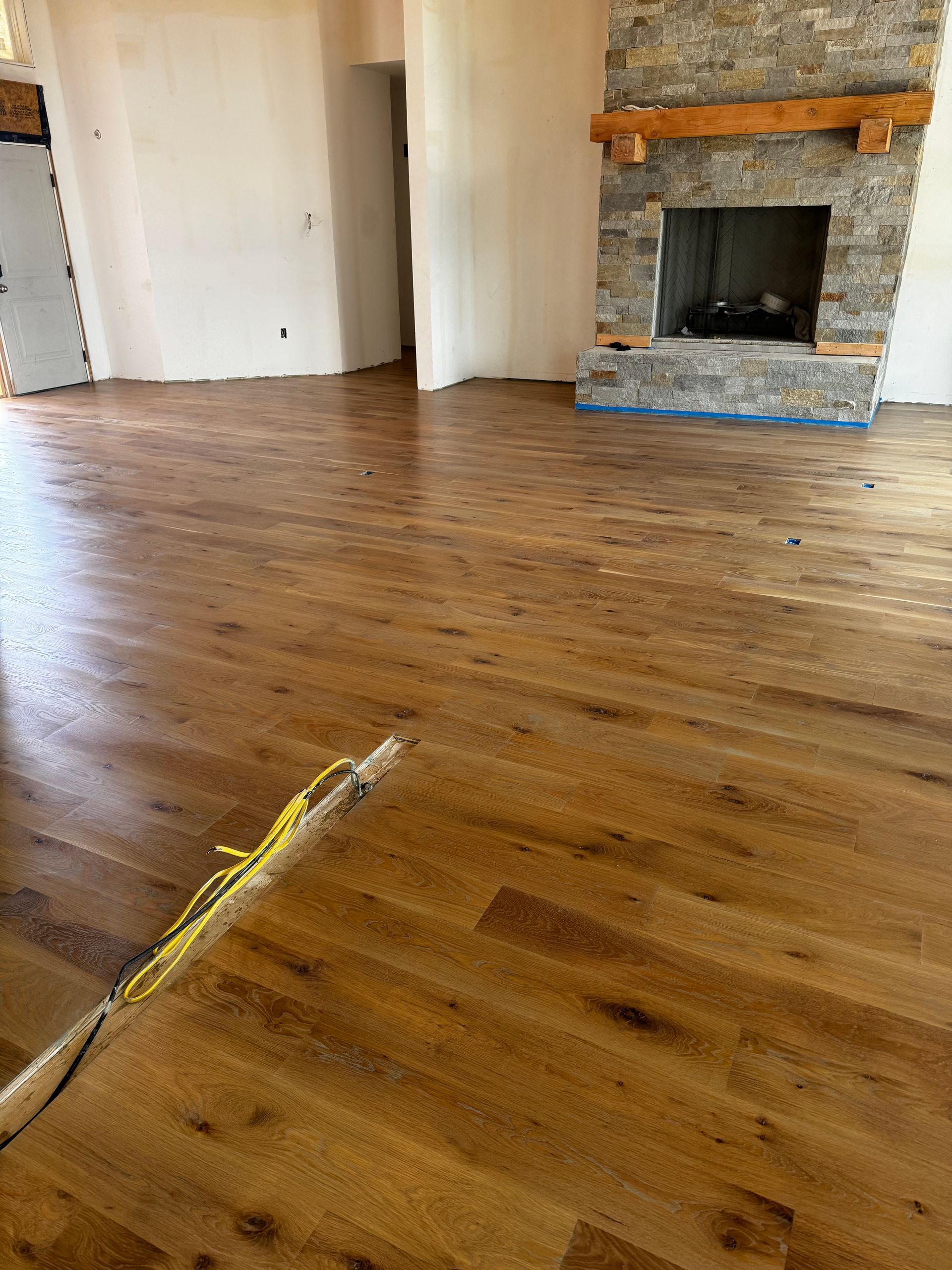 Empty room with hardwood floor and stone fireplace, yellow tape across the foreground