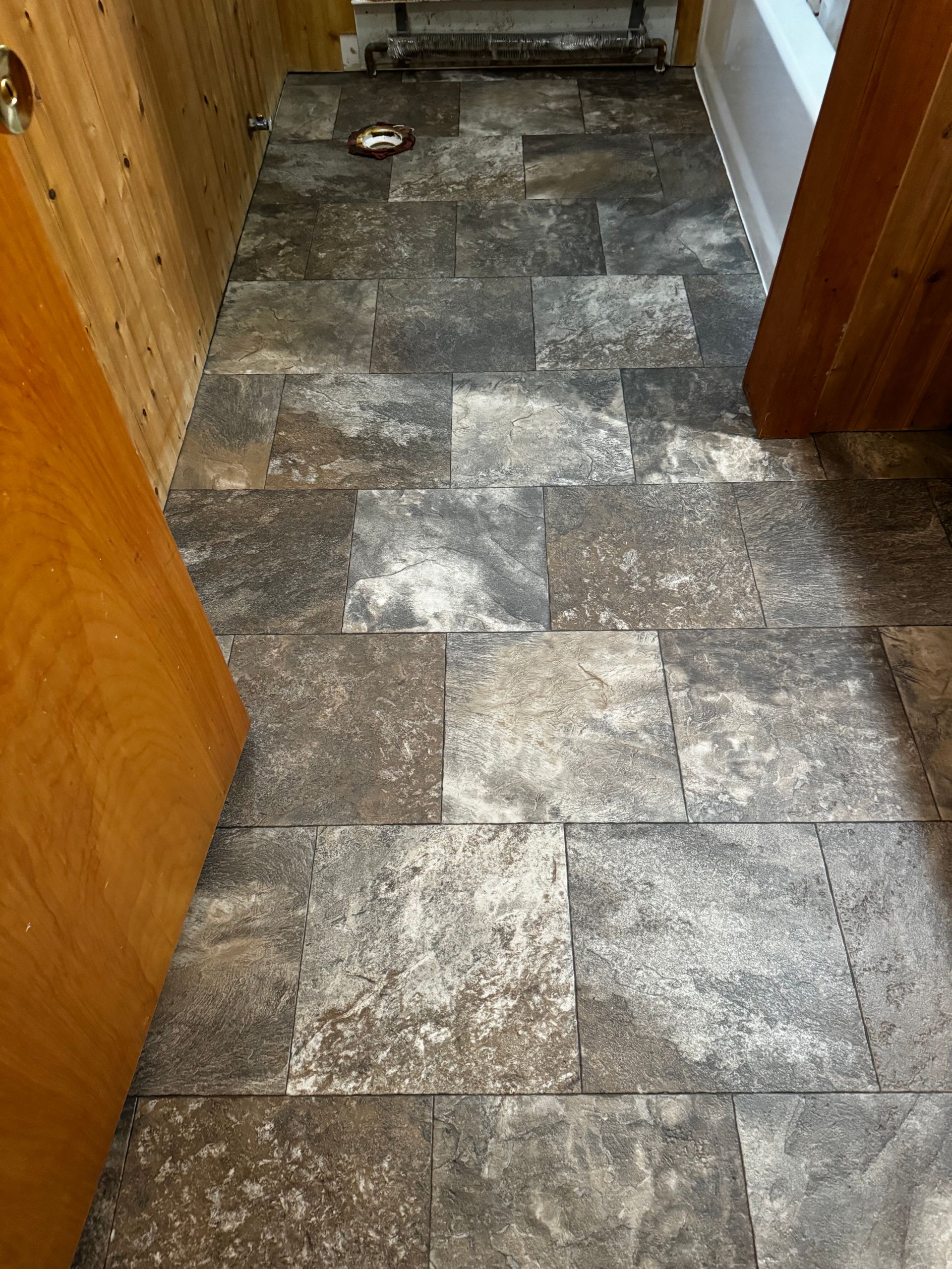 Narrow hallway with gray stone-look tile flooring and wooden door frames.
