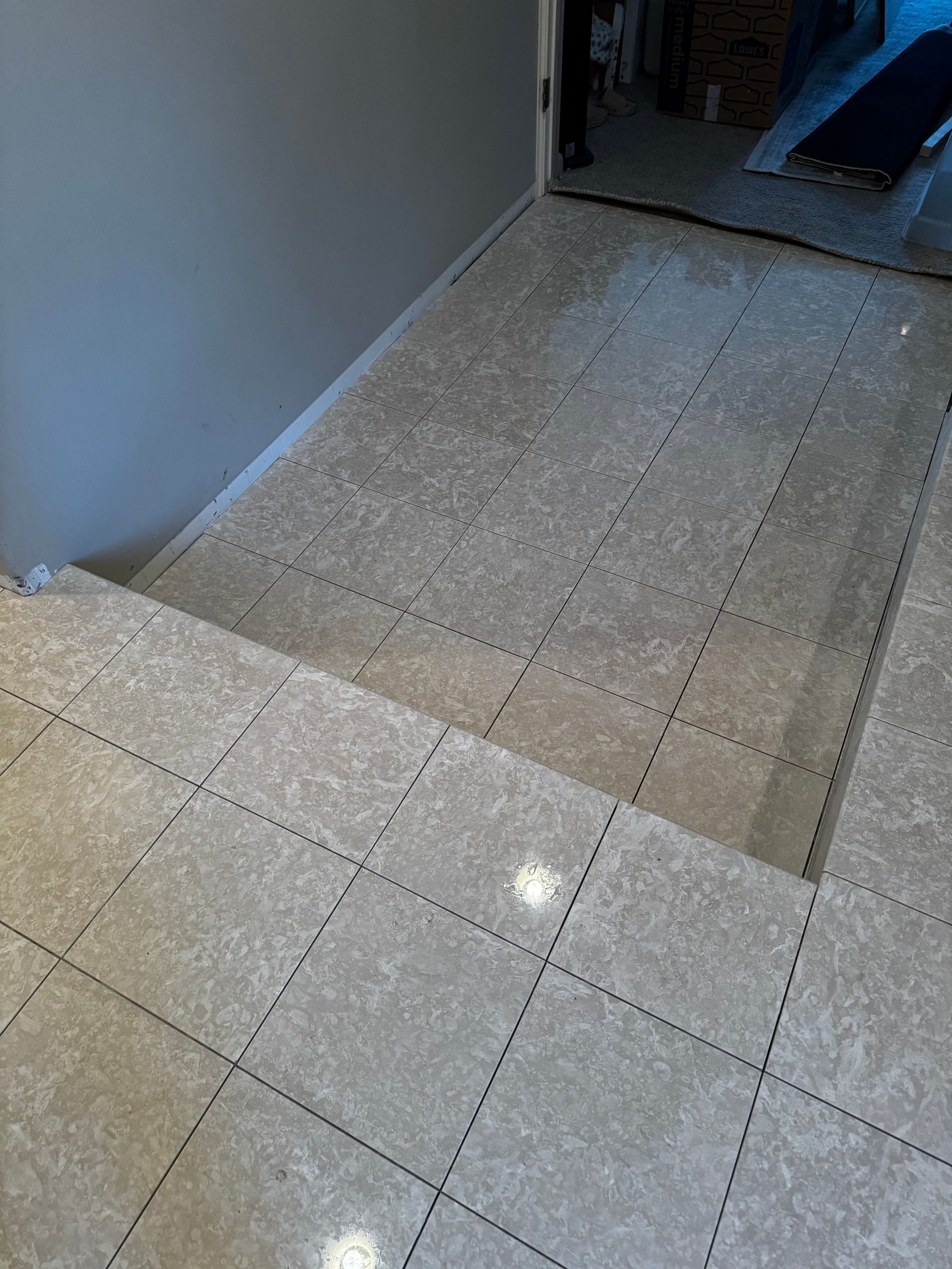 Tiled hallway with stairs in the foreground and a doorway at the end