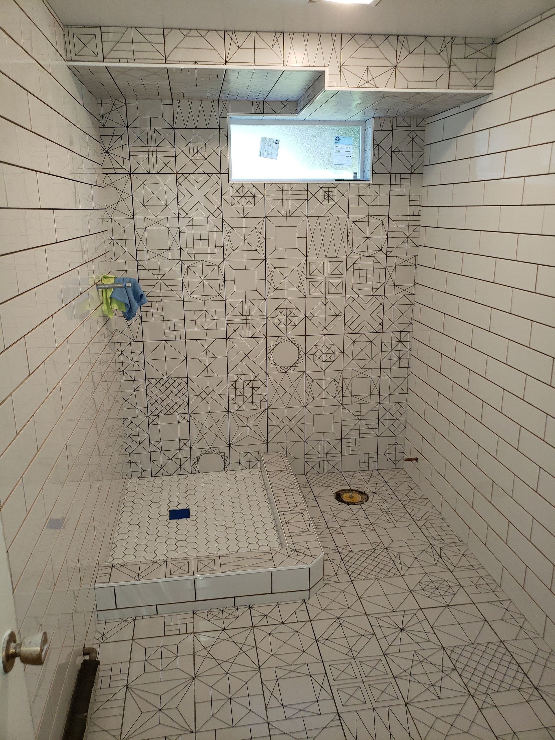 Small white-tiled bathroom with a shower and tiny frosted window.
