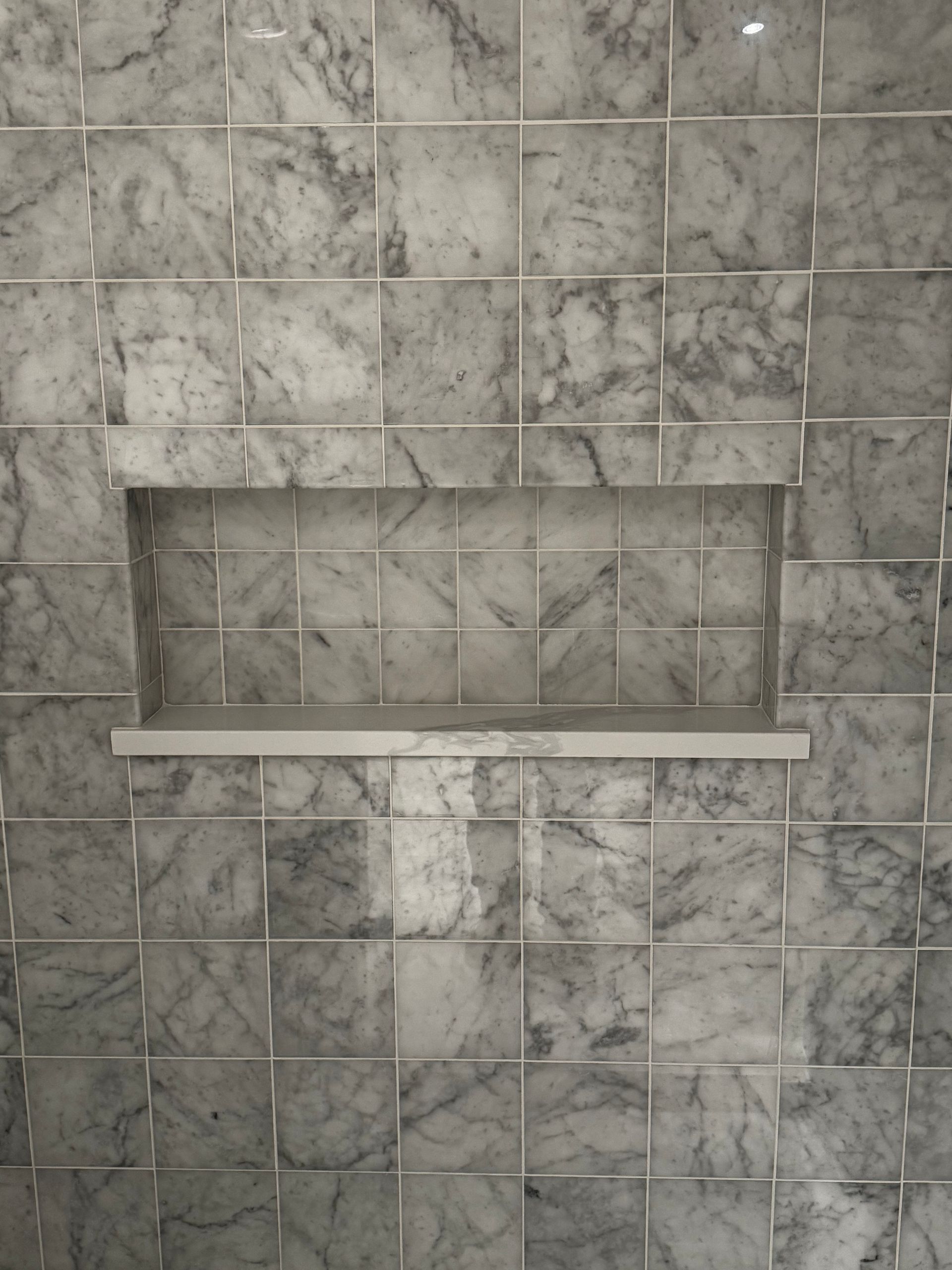 Gray tiled wall with a small recessed shelf and ledge.