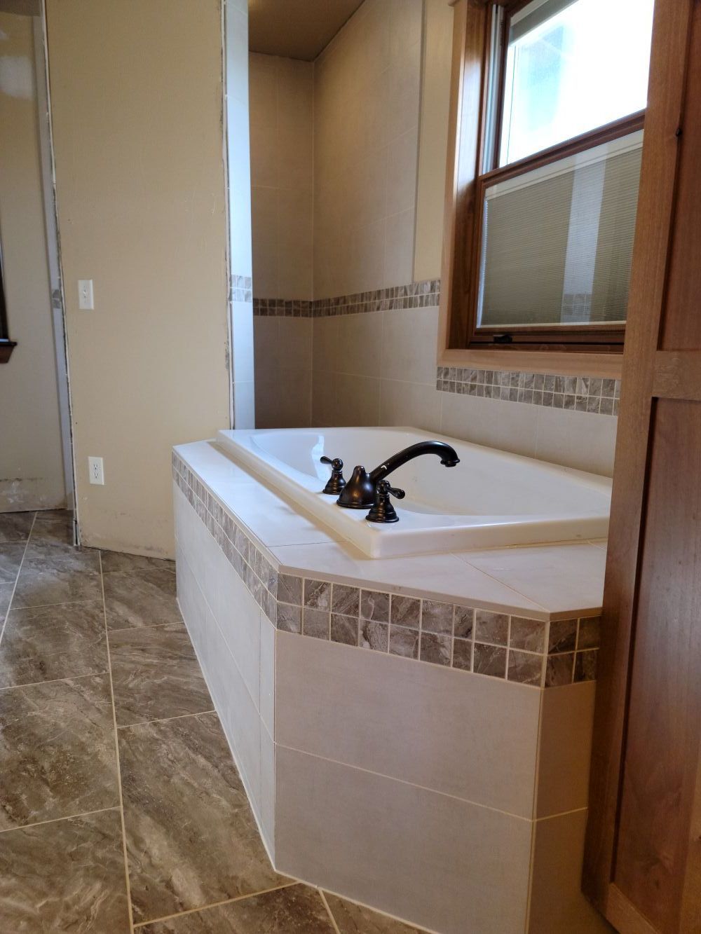 Bathroom with a beige tiled soaking tub, white countertop, and window air conditioner.