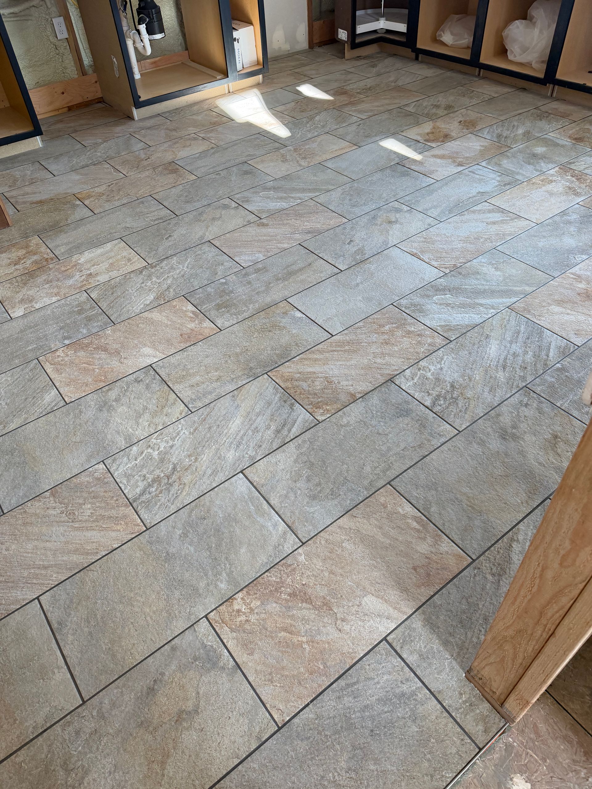 Stone tile floor in an unfinished room with wooden door frames and sunlight patches