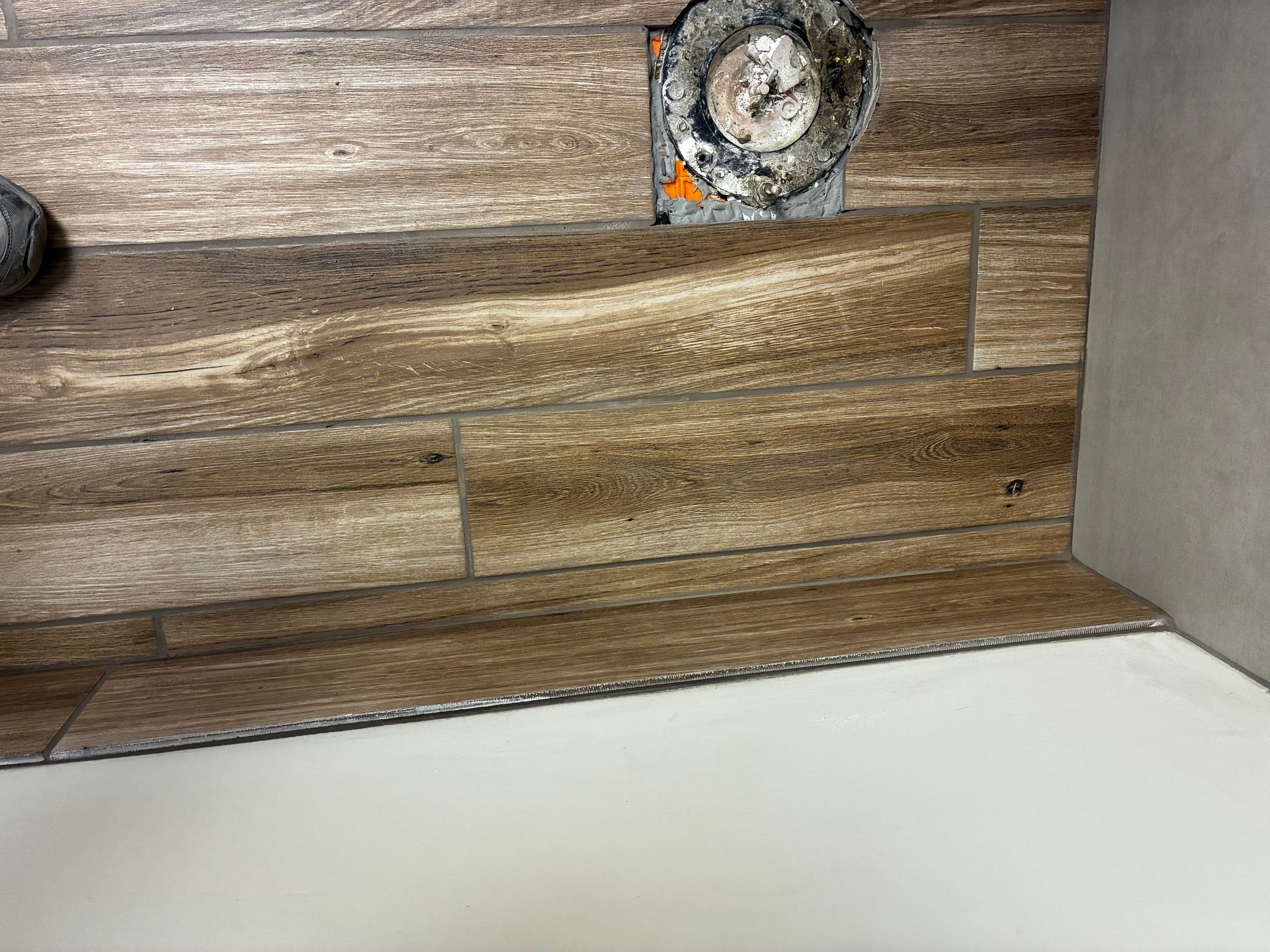 Wood-look wall panel with a small round fixture or hole near the top and a white floor below