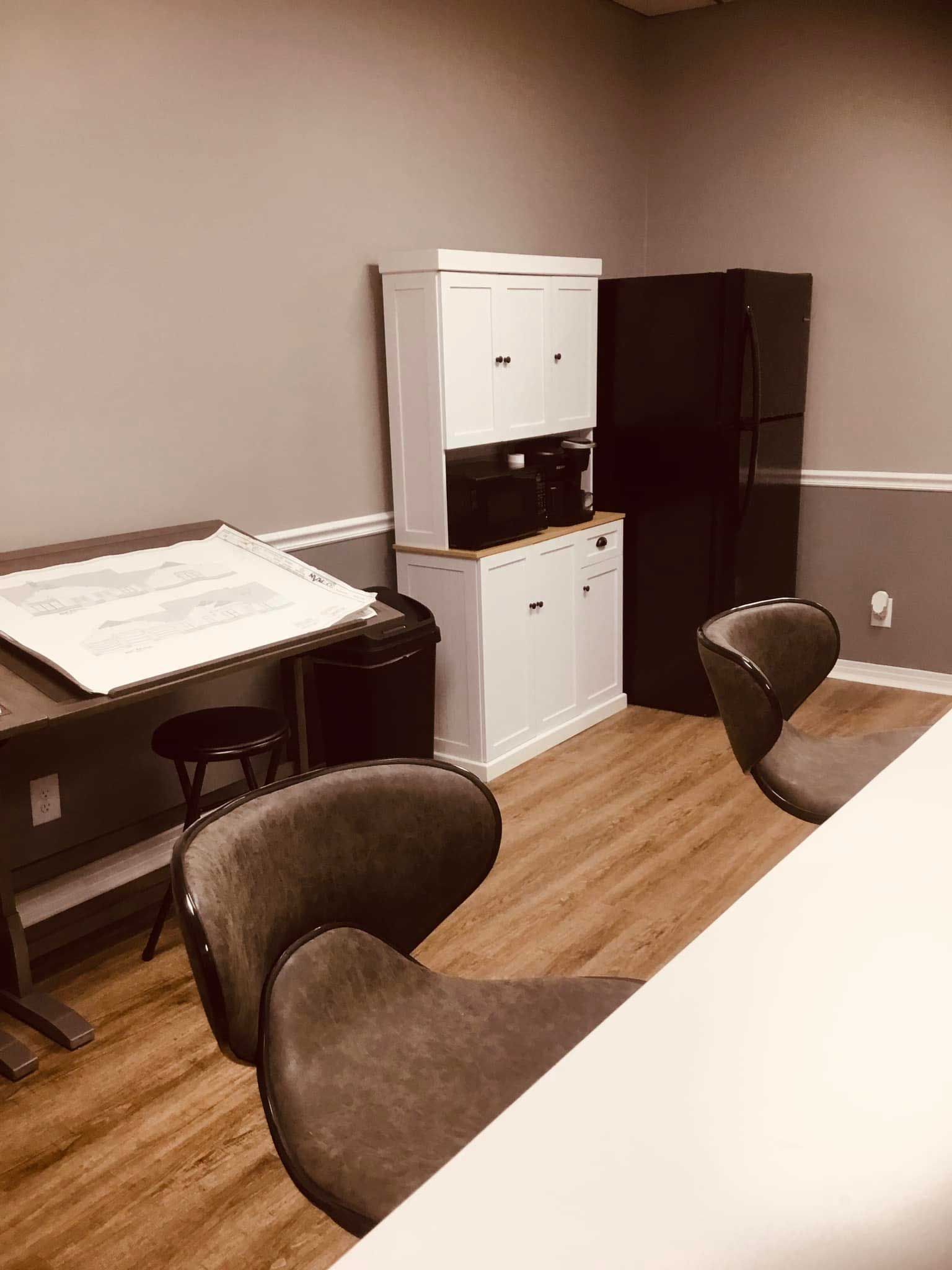 A kitchen with a refrigerator , cabinets , chairs and a table.