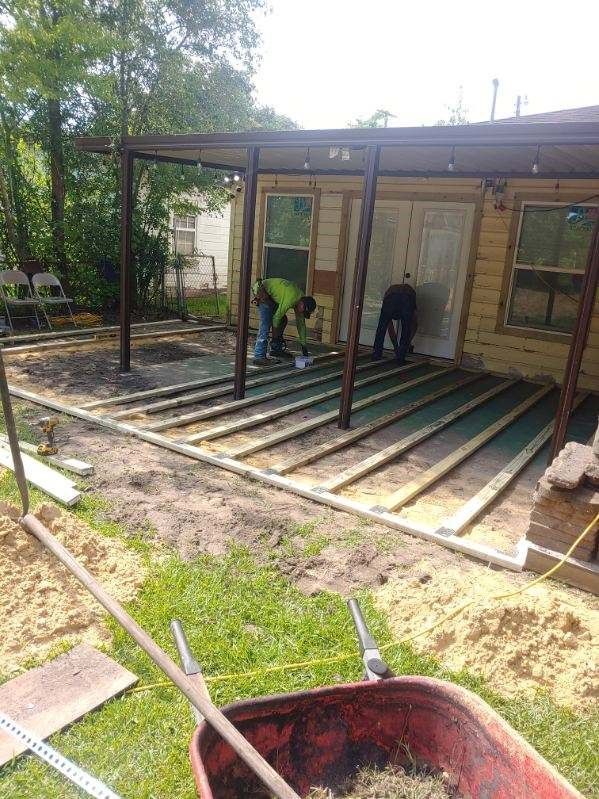 A couple of men are working on a deck in front of a house.