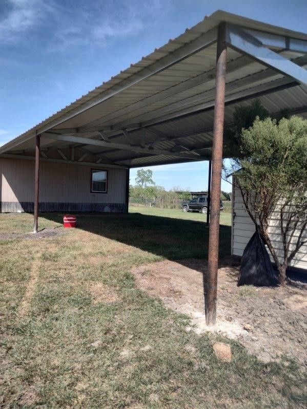 A carport is sitting in the middle of a grassy field.
