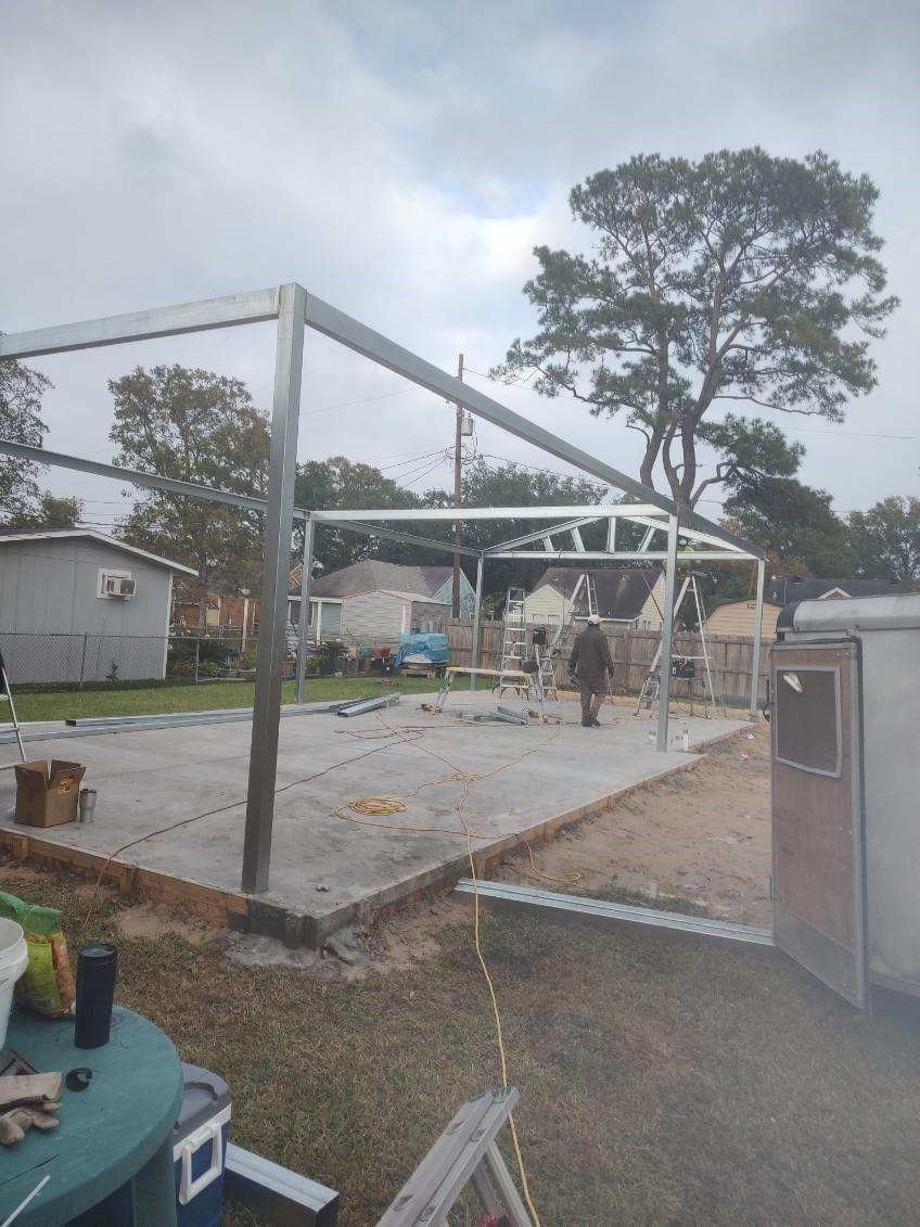 A man is working on a metal structure in a backyard.