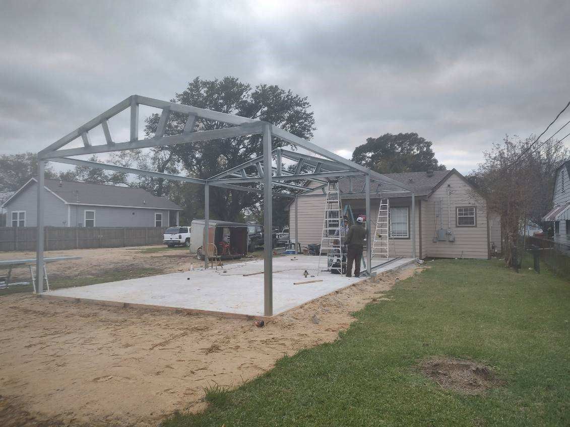 A metal structure is being built in the backyard of a house.