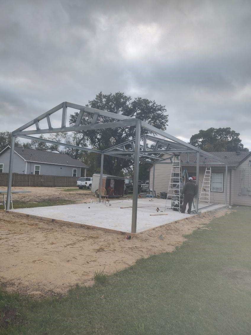 A metal structure is being built in the backyard of a house.