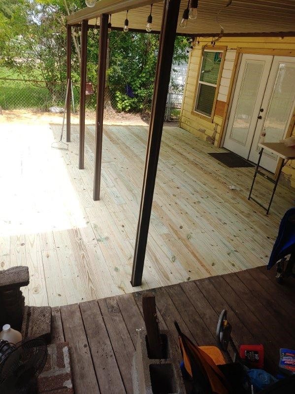 A wooden deck is being built in front of a yellow house.