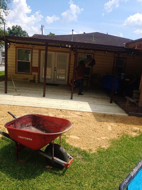 A red wheelbarrow is sitting in front of a house.